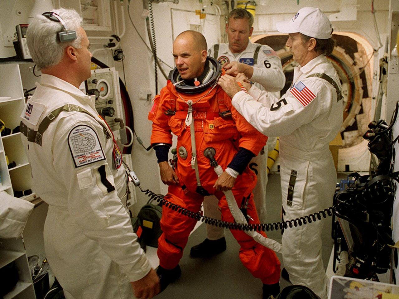 KENNEDY SPACE CENTER, Fla. - STS-105 Pilot Rick Sturckow is assisted with his launch and entry suit before he enters Space Shuttle Discovery for launch. Helping him are (left) Orbiter Vehicle Closeout Chief Chris Meinert, USA Mechanical Technician Al Schmidt (right) and (back) NASA Quality Assurance Specialist Ken Strite. The payload on the STS-105 mission to the International Space Station includes the third flight of the Italian-built Multi-Purpose Logistics Module Leonardo, delivering additional scientific racks, equipment and supplies for the Space Station, and the Early Ammonia Servicer (EAS) tank. The EAS, which will be attached to the Station during two spacewalks, contains spare ammonia for the Station’s cooling system. Also, the Expedition Three crew is aboard to replace the Expedition Two crew on the International Space Station, who will be returning to Earth aboard Discovery after a five-month stay on the Station