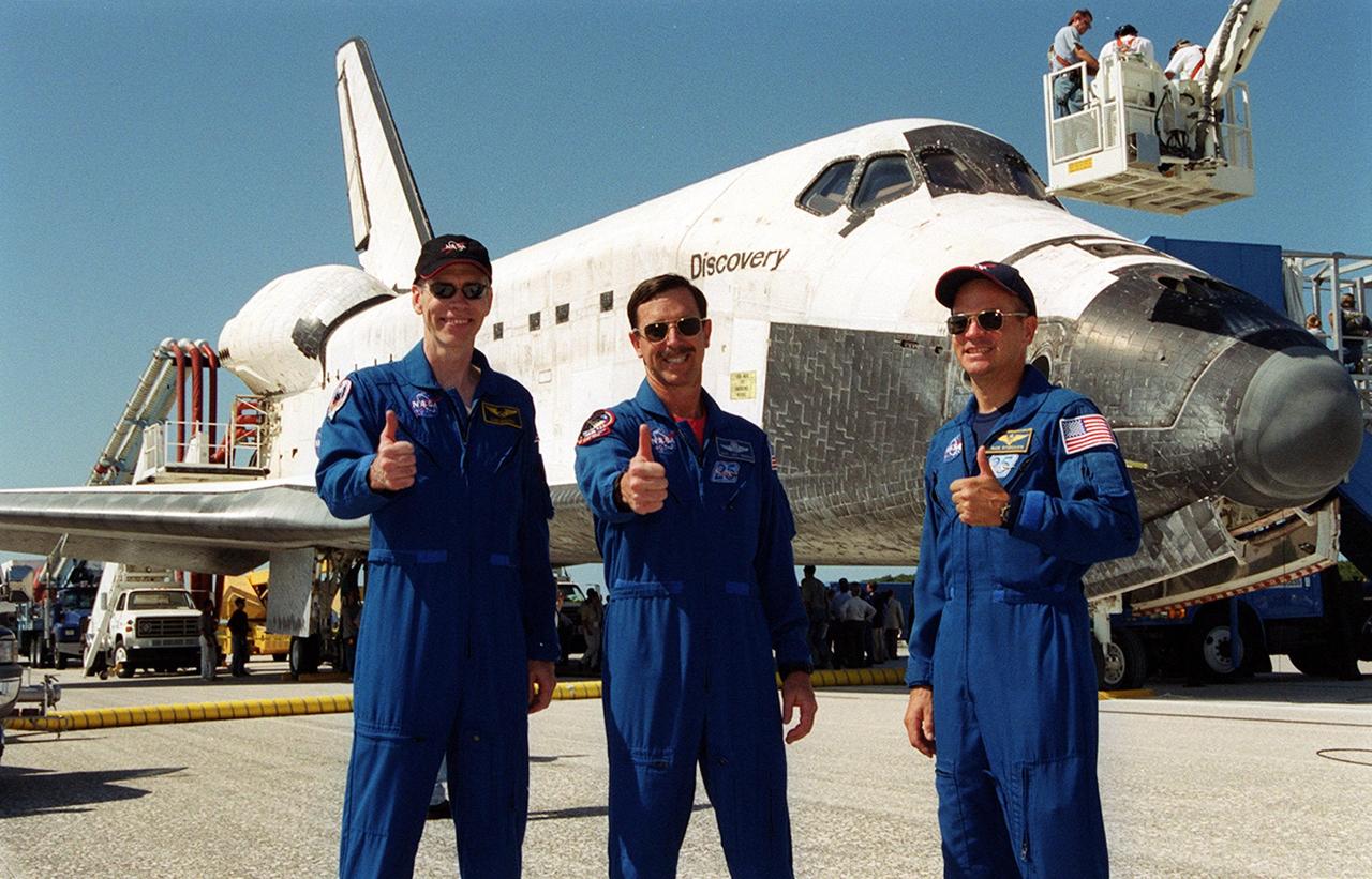 KENNEDY SPACE CENTER, Fla. - Following the landing of mission STS-105, from left, Mission Specialist Daniel Barry, Commander Scott "Doc" Horowitz, and Pilot Frederick "Rick" Sturckow give a thumbs up in front of Space Shuttle Discovery on KSC's Shuttle Landing Facility runway 15, as post-landing safing operations continue on the orbiter. Main gear touchdown was at 2:22:58 p.m. EDT; wheel stop, at 2:24:06 p.m. EDT. The 11-day, 21-hour, 12-minute STS-105 mission accomplished the goals set for the 11th flight to the International Space Station: swapout of the resident Station crew; delivery of equipment, supplies and scientific experiments; and installation of the Early Ammonia Servicer and heater cables for the S0 truss on the Station. Discovery traveled 4.3 million miles on its 30th flight into space, the 106th mission of the Space Shuttle program. Out of five missions in 2001, the landing was the first to occur in daylight at KSC.