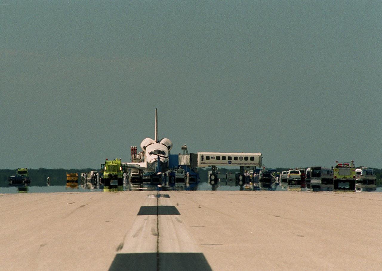 KENNEDY SPACE CENTER, Fla. -- On KSC’s Shuttle Landing Facility runway 15 following mission STS-105, specially designed vehicles and a team of up to 150 trained personnel gather around Discovery for safing operations, checking for toxic or hazardous gases, and introducing purge air to cool the vehicle and humidified air conditioning to the payload bay and other cavities to remove any residual explosive or toxic fumes that may be present. Some personnel will assist the STS-105 and Expedition Two crews in disembarking from the orbiter via the Crew Transfer Vehicle (at right).  KSC support personnel will prepare the orbiter for ground tow operations, installing switch guards and removing data packages from any onboard experiments.  Main gear touchdown was at 2:22:58 p.m. EDT; wheel stop, at 2:24:06 p.m. EDT. The 11-day, 21-hour, 12-minute mission accomplished the goals set for the 11th flight to the International Space Station: swapout of the resident Station crew; delivery of equipment, supplies and scientific experiments; and installation of the Early Ammonia Servicer and heater cables for the S0 truss on the Station. Discovery traveled 4.3 million miles on its 30th flight into space, the 106th mission of the Space Shuttle program. Out of five missions in 2001, the landing was the first to occur in daylight at KSC