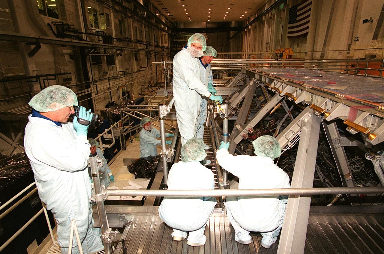 KENNEDY SPACE CENTER, Fla. --  In the Operations and Checkout Building, during a Crew Equipment Interface Test,  members of the STS-110 crew check out Integrated Truss Structure (ITS) S0, which will be part of the payload on their mission.  At left is Mission Specialist Jerry L. Ross, with a camera.  Standing (center) are Mission Specialists Steven L. Smith and Rex J. Walheim.  Other crew members (not shown) are Commander Michael J. Bloomfield, Pilot Stephen N. Frick, and Missin Specialists Ellen Ochoa and Lee M. Morin.    The ITS S0 is part of the payload on the mission. It is the center segment they will be installing on the International Space Station, part of the 300-foot (91-meter) truss attached to the U.S. Lab. By assembly completion, four more truss segments will attach to either side of the S0 truss.  STS-110 is currently scheduled to launch in February 2002
