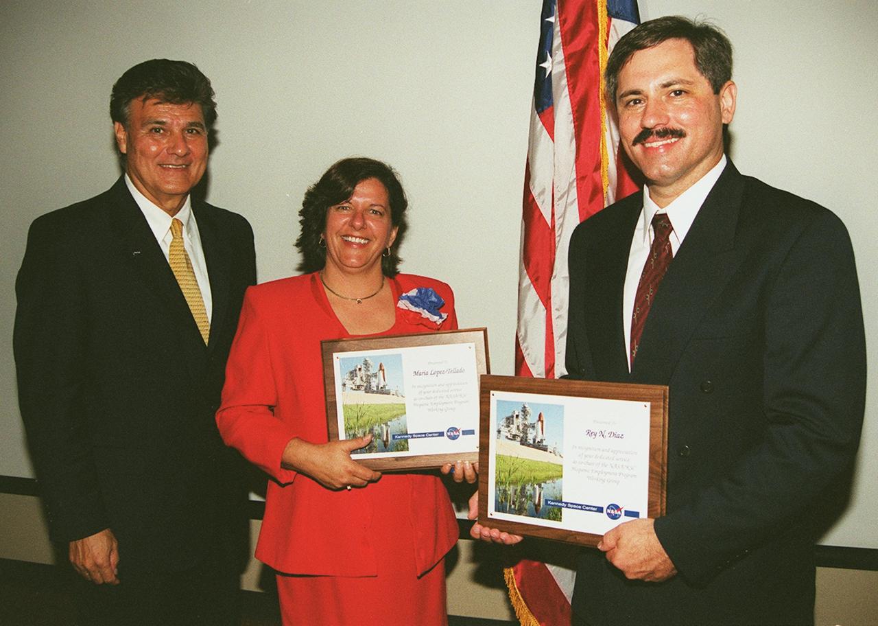 KENNEDY SPACE CENTER, Fla. -- Maria Lopez-Tellado (center) and Rey N. Diaz (right) display the plaques they received at the annual Hispanic Heritage  Month Celebration, held at the Kurt Debus Conference Facility at KSC.  The two were recognized for their efforts as chairs of the event, which featuraed a luncheon and comments by Deputy Center Director Jim Jennings and Miguel Rodriquez, chief, Integration Office, of the Joint Performance Management Office.  Joseph Tellado (left), International Space Station/Payload Processing, led the pledge of allegiance and invocation. The Merrit Island High School ROTC provided the color guard.  The event was sponsored by the Hispanic Employment Program Working Group at KSC