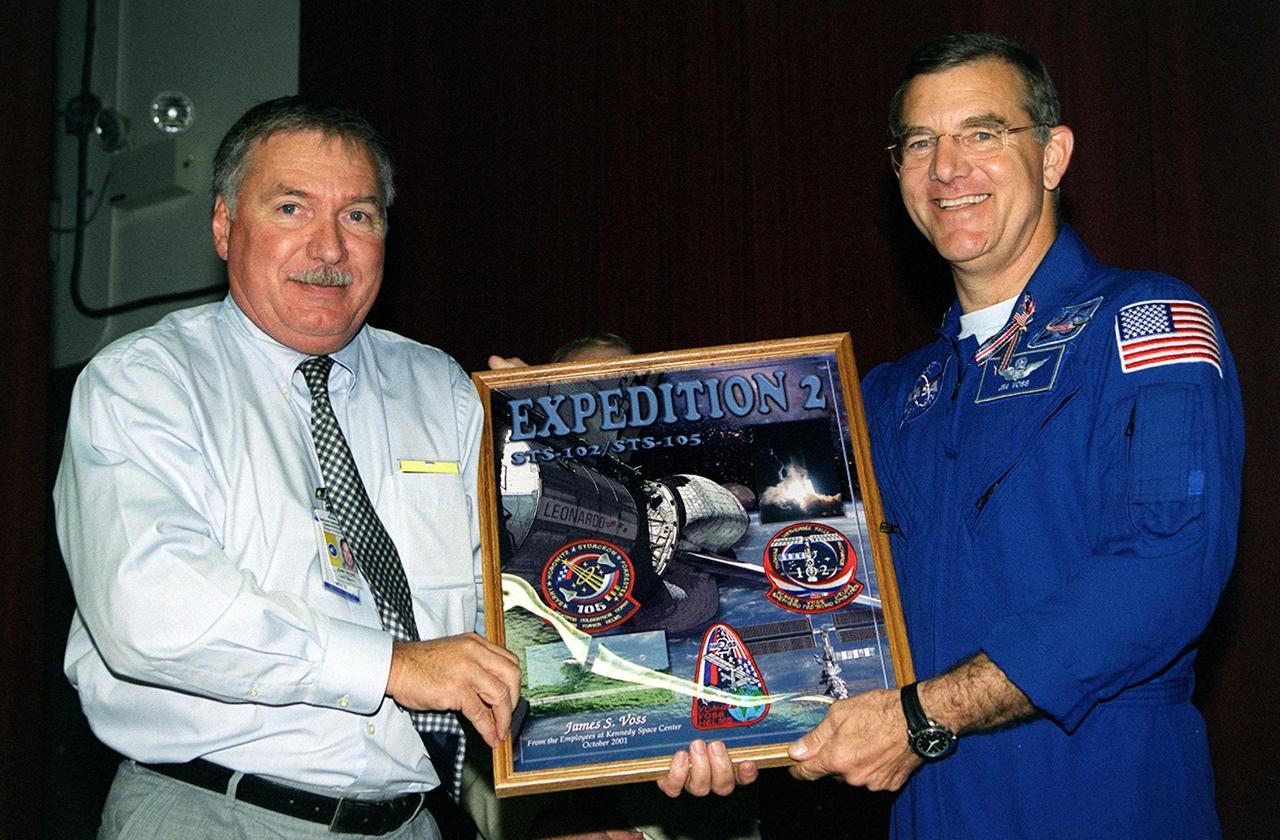 KENNEDY SPACE CENTER, Fla. -- J.J. "Tip" Talone Jr., director of KSC's International Space Station/Payload Processing, presents Expedition 2 crew member Jim Voss with a photo plaque from employees commemorating his stay aboard the Space Station. The Expedition 2 crew, which included astronaut Susan Helms and cosmonaut Yury Usachev , made the space voyage to the Station on mission STS-102 in March 2001. After five months on the Station, they returned to Earth, at the KSC Shuttle Landing Facility, on mission STS-105 in August 2001