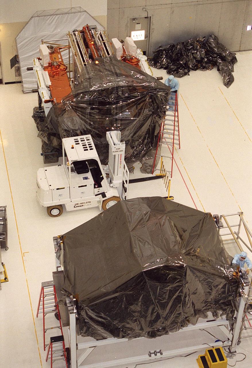 KENNEDY SPACE CENTER, Fla. -- In the Vertical Processing Facility, workers remove the wrapping from several components of the STS-109 payload. The purpose of the mission is servicing the Hubble Space Telescope. The primary servicing tasks of the mission are to replace Solar Array 2 with Solar Array 3, replace the Power Control Unit, remove the Faint Object Camera and install the Advanced Camera for Surveys, install the NICMOS Cooling System, and install New Outer Blanket Insulation on bays 5 through 8. Mission STS-109 is scheduled for launch in mid-February 2002