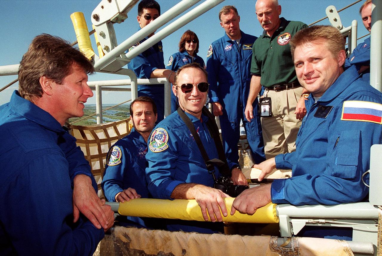 KENNEDY SPACE CENTER, Fla. -- The STS-108 and Expedition 4 crews get emergency egress training on Launch Pad 39B.  Seated in the slidewire basket are astronauts Daniel W. Bursch and Carl E. Walz, with Expedition 4 Commander Yuri Onufrienko.  Standing in the background are STS-108 Mission Specialists Daniel M. Tani and Linda A. Godwin, and Commander Dominic L. Gorie.  At the far right is astronaut Michael Fincke, part of a backup crew for Expedition 4. Crew members are at KSC for Terminal Countdown Demonstration Test activities that include a simulated launch countdown, plus the emergency exit training from the orbiter and launch pad. STS-108 is a Utilization Flight that will carry the replacement Expedition 4 crew to the International Space Station, as well as the Multi-Purpose Logistics Module Raffaello, filled with supplies and equipment.  The l1-day mission is scheduled for launch Nov. 29 on Space Shuttle Endeavour