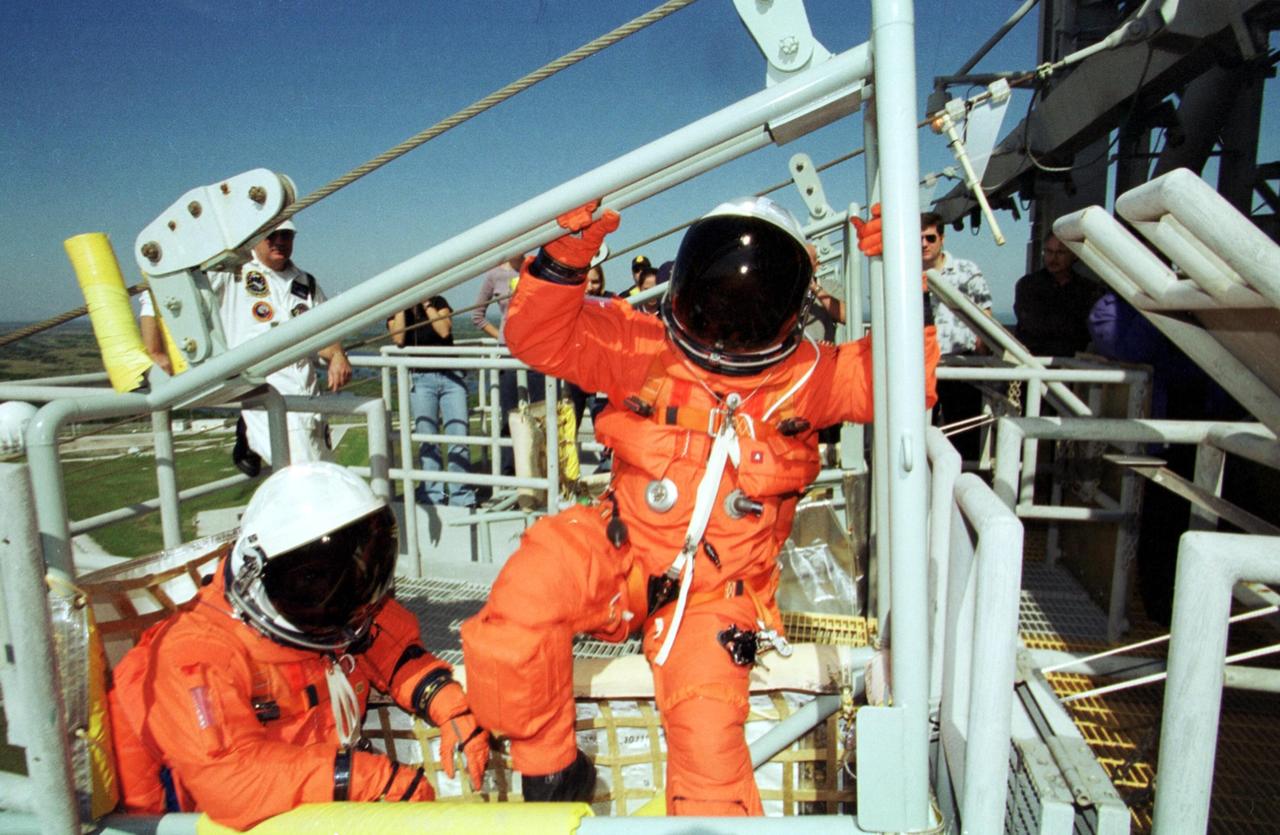 KENNEDY SPACE CENTER, Fla. --  STS-108 Pilot Mark E. Kelly (left) takes a seat in the slidewire basket while Commander Dominic L. Gorie climbs in at the front.   The basket is part of the emergency egress system from the 195-foot level of the Fixed Service Structure on Launch Pad 39B. The training is part of Terminal Countdown Demonstration Test activities that also include a simulated launch countdown.. Launch of  Space Shuttle Endeavour on mission STS-108 is scheduled for Nov. 29 at 7:44 p.m. EST