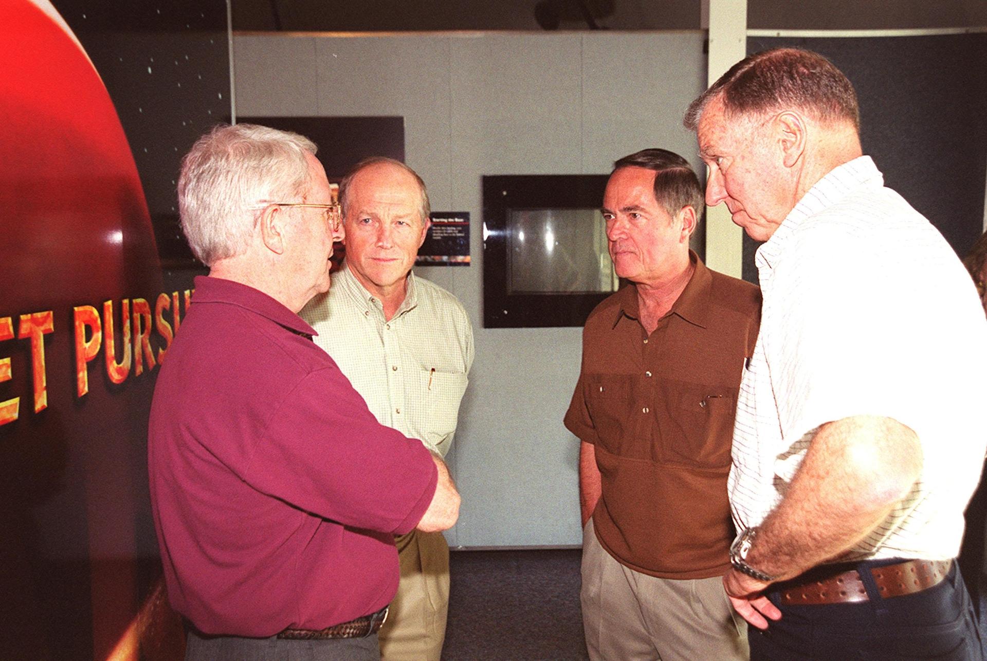 Richard Truly, Rick Hauck, Bob Crippen and Joe Engle stand in a circle chatting during a visit at the Kennedy Space Center Visitor Complex.