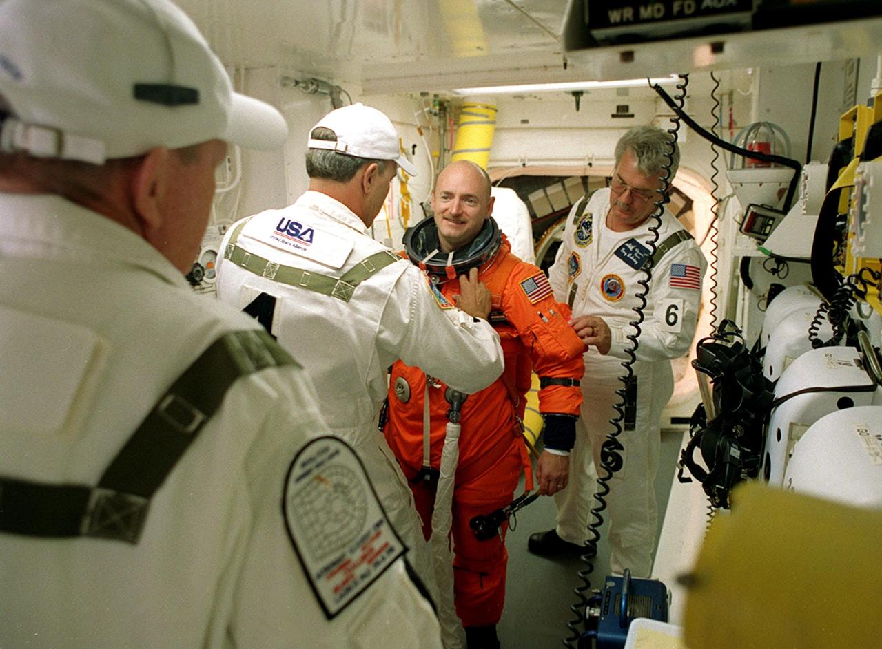KENNEDY SPACE CENTER, Fla. -  STS-108 Pilot Mark E. Kelly is helped with his launch and entry suit before entering Endeavour.   The main goals of the mission are to carry the Expedition 4 crew to the International Space Station as replacement for Expedition 3; carry the Multi-Purpose Logistics Module Raffaello filled with water, equipment and supplies; and  install thermal blankets over equipment at the base of the ISS solar wings. STS-108 is the final Shuttle mission of 2001 and the 107th Shuttle flight overall.  It is the 12th flight to the Space Station.  Launch is scheduled for 5:19 p.m. EST (22:19 GMT) Dec. 5, 2001, from Launch Pad 39B