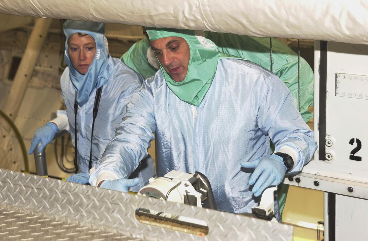 KENNEDY SPACE CENTER, FLA. -- STS-112 Mission Specialist David Wolf (right) and Pilot Pamela Melroy (left) look at equipment in the payload bay of Atlantis during a Crew Equipment Interface Test at KSC. In the background, right, is Commander Jeffrey Ashby. STS-112 is the 15th assembly flight to the International Space Station and will be ferrying the S1 Integrated Truss Structure. The S1 truss is the first starboard (right-side) truss segment, whose main job is providing structural support for the radiator panels that cool the Space Station's complex power system. The S1 truss segment also will house communications systems, external experiment positions and other subsystems. The S1 truss will be attached to the S0 truss. STS-112 is currently scheduled for launch Aug. 22, 2002