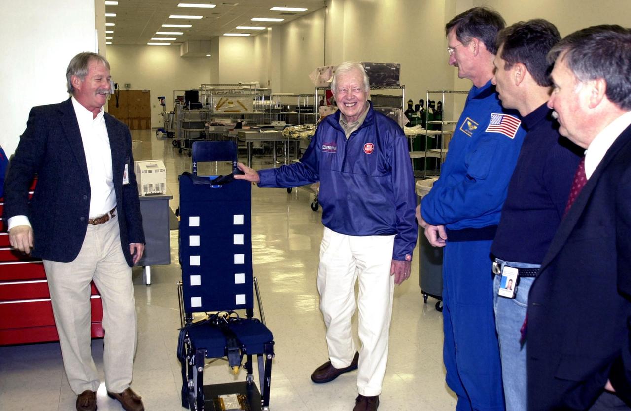 KENNEDY SPACE CENTER, FLA. - During a tour of KSC, former President Jimmy Carter is shown the current version of a lightweight mission specialist seat.  From left to right are Ron Woods, a technician in the Flight Crew Equipment Facility; Carter; astronaut Joseph Tanner; another KSC employee; and Tip Talone, director of Payload Processing, International Space Station