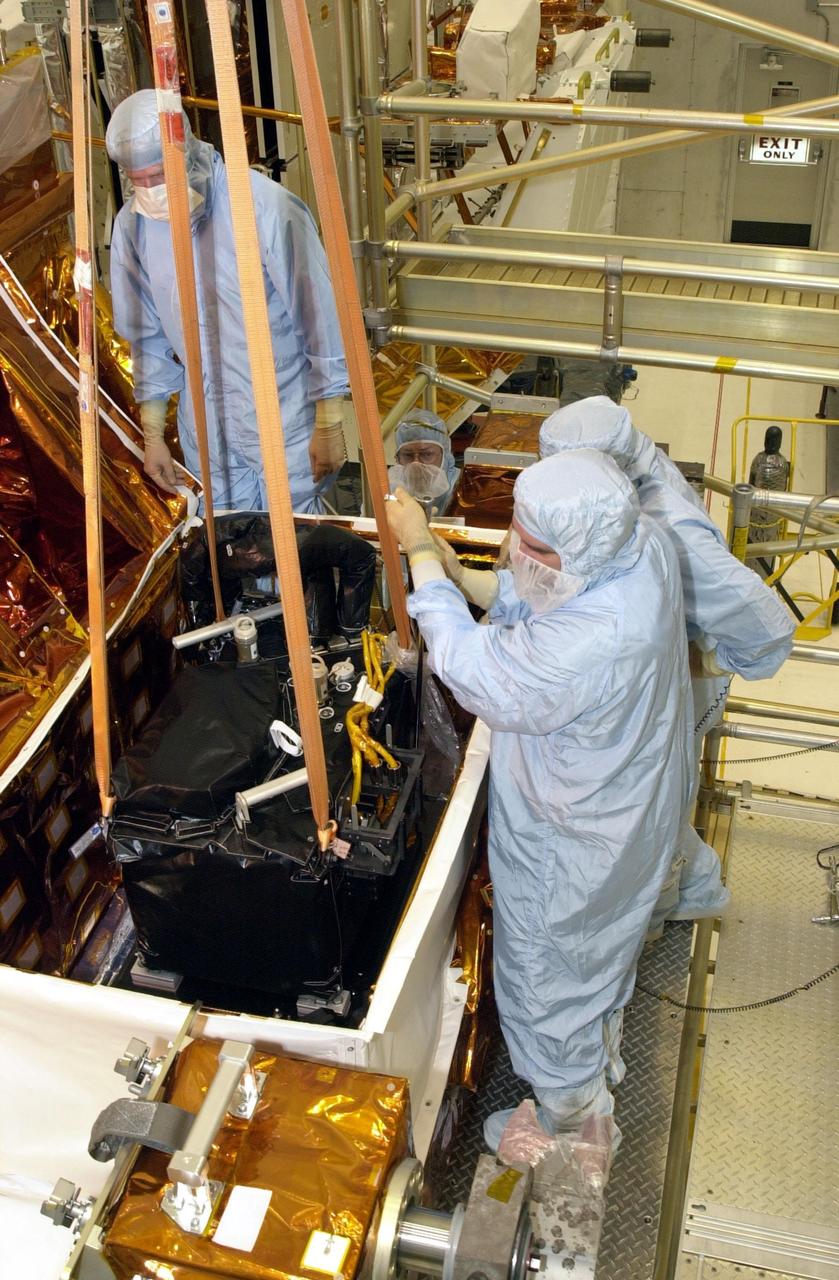 KENNEDY SPACE CENTER, FLA. -- In the Vertical Processing Facility, workers help guide the Near Infrared Camera and Multi-Object Spectrometer (NICMOS) Cooling System into an protective enclosure on a payload carrier. NICMOS II is part of the payload on mission STS-109, the Hubble Servicing Telescope Mission. It is a new experimental cooling system consisting of a compressor and tiny turbines. With the experimental cryogenic system, NASA hopes to re-cool the infrared detectors to below -315 degrees F (-193 degrees Celsius). NICMOS II was previously tested aboard STS-95 in 1998. It could extend the life of the Hubble Space Telescope by several years. Astronauts aboard Columbia on mission STS-109 will be replacing the original NICMOS with the newer version. Launch of mission STS-109 is scheduled for Feb. 28, 2002