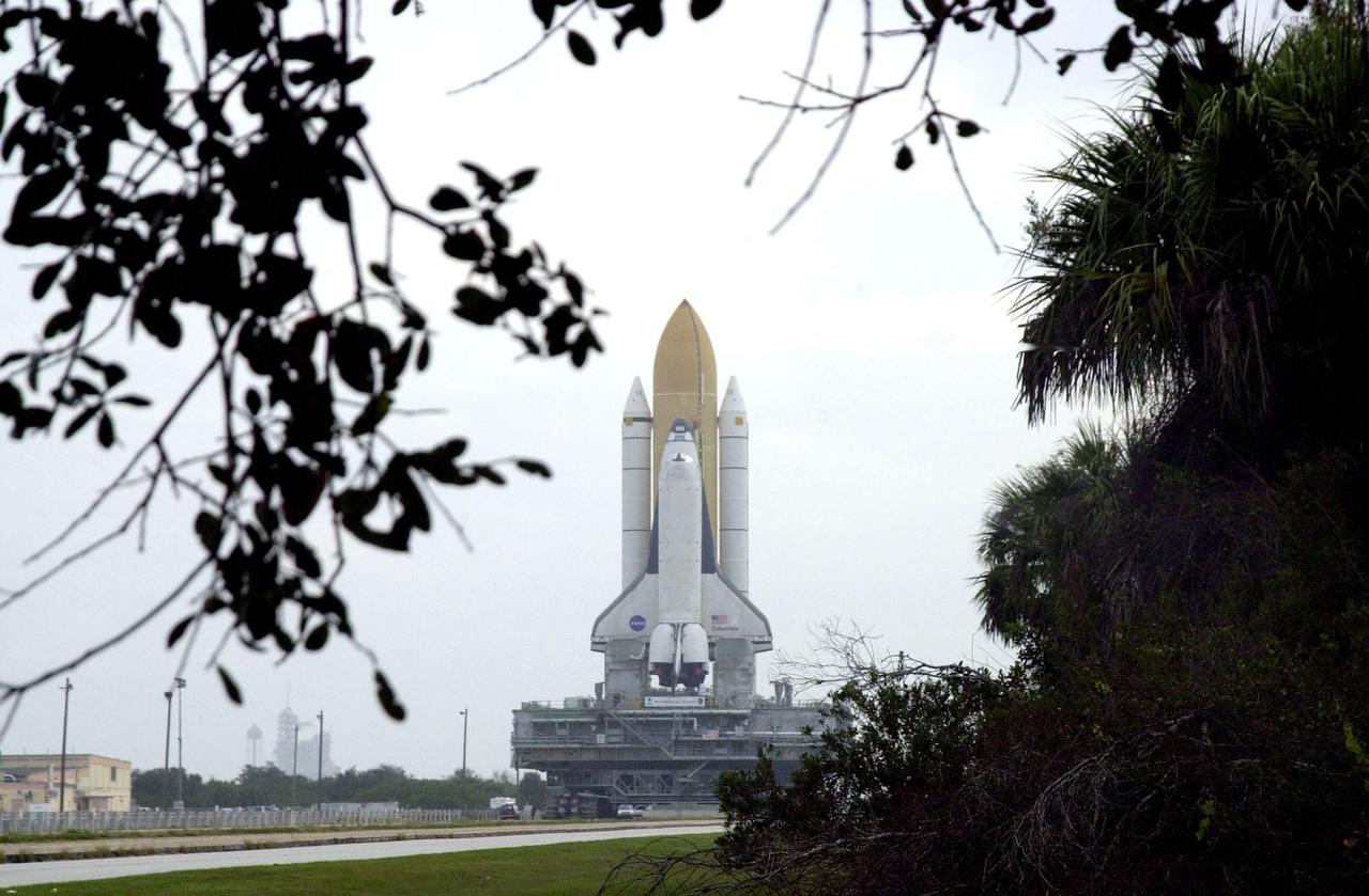 KENNEDY SPACE CENTER, FLA. -- Framed by trees and palmetto scrub, Space Shuttle Columbia is viewed atop its Mobile Launcher Platform as it rolls out to Launch Pad 39A. Underneath is the crawler-transporter, which carries the multi-ton vehicles to the launch pad. Columbia is scheduled to be launched Feb. 28 on mission STS-109, a Hubble Servicing Mission. The goal of the mission is to replace Solar Array 2 with Solar Array 3, replace the Power Control Unit, remove the Faint Object Camera and install the ACS, install the Near Infrared Camera and Multi-Object Spectrometer (NICMOS) Cooling System, and install New Outer Blanket Layer insulation
