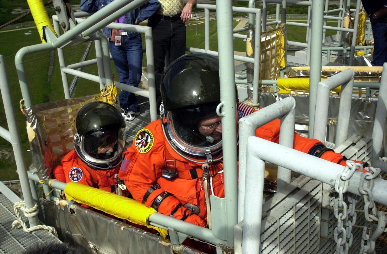 KENNEDY SPACE CENTER, FLA. -- As part of Terminal Countdown Demonstration Test activities, the STS-109 crew practices emergency exit from the Shuttle. Seated in the slidewire basket at the 195-foot level of the Fixed Service Structure are Mission Specialists Nancy Currie (left) and John Grunsfeld (reaching for the release lever). The TCDT also includes a simulated launch countdown. STS-109 is a Hubble Space Telescope Servicing Mission, with goals to replace Solar Array 2 with Solar Array 3, replace the Power Control Unit, remove the Faint Object Camera and install the Advanced Camera for Surveys (ACS), install the Near Infrared Camera and Multi-Object Spectrometer (NICMOS) Cooling System, and install New Outer Blanket Layer insulation. The 11-day mission will require five spacewalks to perform the tasks. Launch of STS-109 aboard Space Shuttle Columbia is scheduled for Feb. 28, 2002