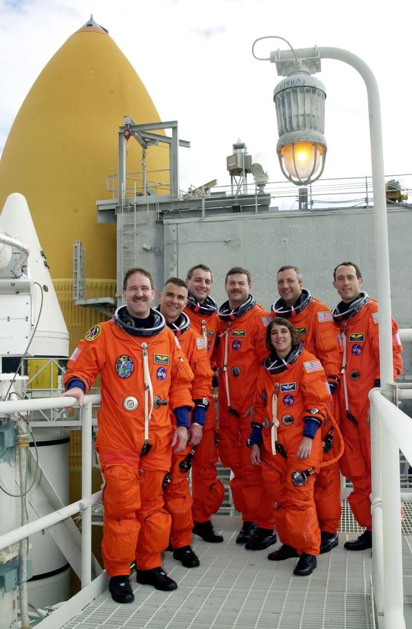 KENNEDY SPACE CENTER, FLA. --  After emergency exit practice on Launch Pad 39A, the STS-109 crew poses for a photo on the 225-foot level of the Fixed Service Structure.  Clockwise from left are Mission Specialist John Grunsfeld; Pilot Duane Carey; Mission Specialist Richard Linnehan; Commander Scott Altman; and Mission Specialists Michael Massimino, James Newman and Nancy Currie.   Behind them at left can be seen one of the twin solid rocket boosters and the larger external tank that will propel Columbia and the crew into space. The goal of mission STS-109, a Hubble Servicing Mission, is to replace Solar Array 2 with Solar Array 3, replace the Power Control Unit, remove the Faint Object Camera and install the ACS, install the Near Infrared Camera and Multi-Object Spectrometer (NICMOS) Cooling System, and install New Outer Blanket Layer insulation.  The launch will be the first for Columbia after returning from California where it underwent extensive maintenance, inspections and enhancements. More than 100 upgrades make Columbia safer and more reliable than ever before. Columbia is scheduled to be launched Feb. 28