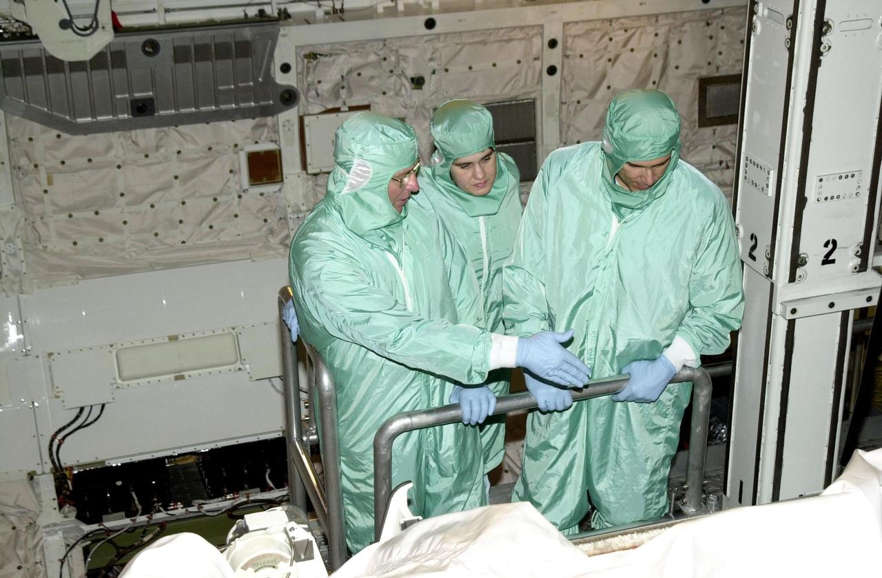 KENNEDY SPACE CENTER, FLA. --  In the Orbiter Processing Facility, STS-110 crew members look over the payload bay of Atlantis during Crew Equipment Integration Test activities, which include familiarization with the vehicle and payload.   From left are Mission Specialist Jerry Ross, a technician, and Mission Specialist Lee Morin.  The mission, 13th assembly flight to the International Space Station, includes the Integrated Truss Structure S0.    The ITS S0 is the center segment on the Space Station, part of the 300-foot (91-meter) truss attached to the U.S. Lab. By assembly completion, four more truss segments will attach to either side of the S0 truss.  STS-110 is scheduled to launch April 4, 2002
