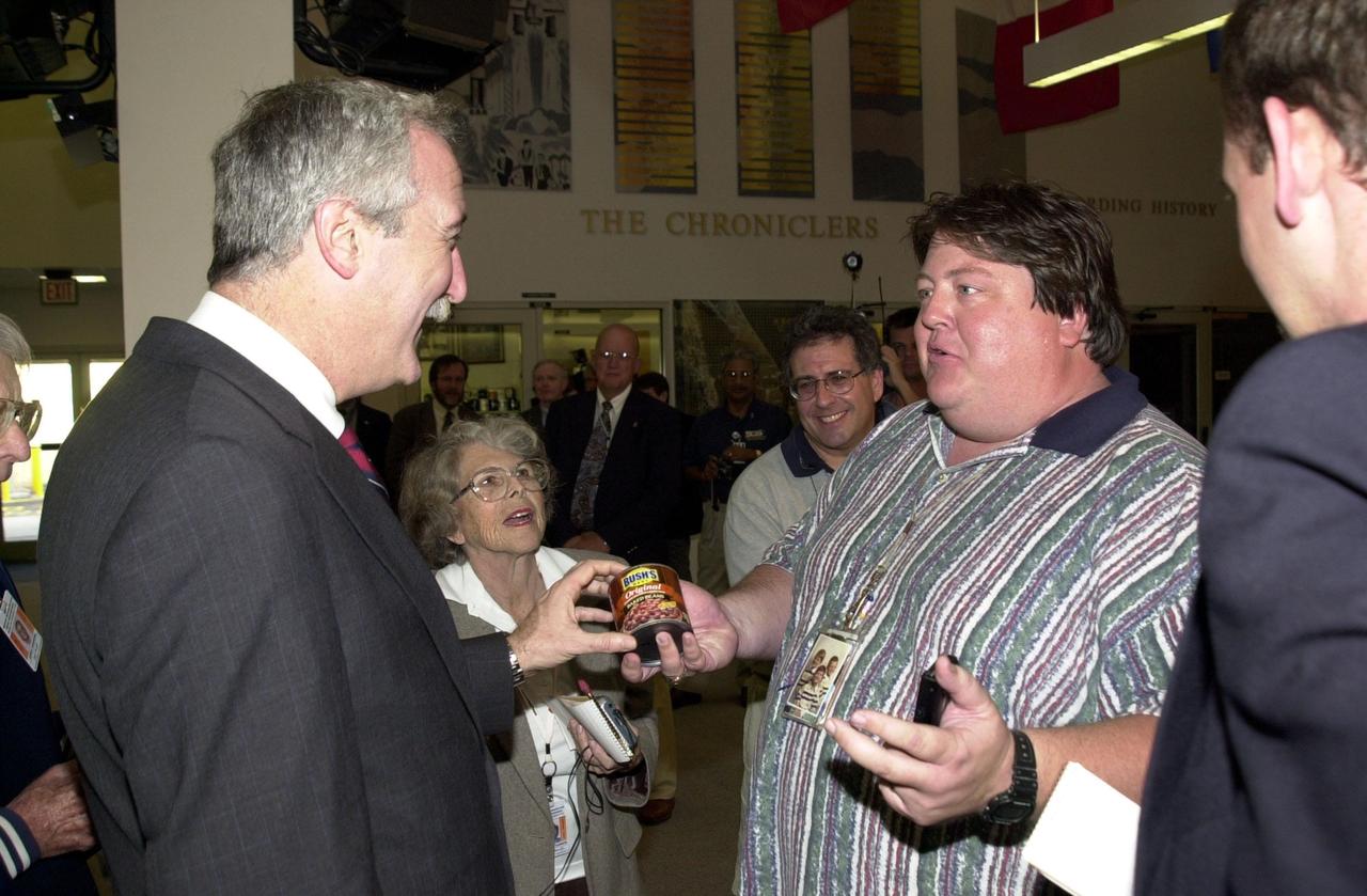 KENNEDY SPACE CENTER, Fla. - The new NASA Administrator Sean O'Keefe (left) is presented with a can of Bush's original baked beans by space reporter Jim Banke in the KSC Newsroom. The administrator was at KSC on an agencywide familiarization tour of NASA field centers. He was nominated for the position as administrator in November 2001 by President George W. Bush. He was sworn in Dec. 21 as the agency's tenth chief