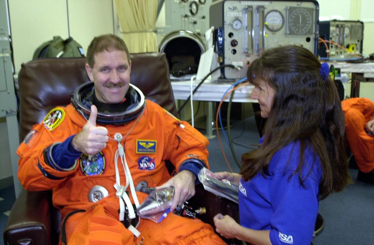 KENNEDY SPACE CENTER, Fla. - During suitup, STS-109 Payload Commander John M. Grunsfeld shows his readiness for launch. Liftoff of Space Shuttle Columbia is scheduled for 6:22 a.m. EST March 1. On mission STS-109, the crew will capture the Hubble Space Telescope using the Shuttle's robotic arm and secure it on a workstand in Columbia's payload bay. Four mission specialists will perform five scheduled spacewalks to complete system upgrades to the telescope. More durable solar arrays, a large gyroscopic assembly to help point the telescope properly, a new telescope power control unit, and a cooling system to restore the use of a key infrared camera and spectrometer unit, which has been dormant since 1999, will all be installed. In addition, the telescope's view of the Universe will be improved with the addition of the Advanced Camera for Surveys (ACS), which replaces the Faint Object Camera, the last of Hubble's original instruments. Mission STS-109 is the 27th flight of the orbiter Columbia and the 108th flight overall in NASA's Space Shuttle program. After the 11-day mission, Columbia is scheduled to land about 4:35 a.m. EST March 12