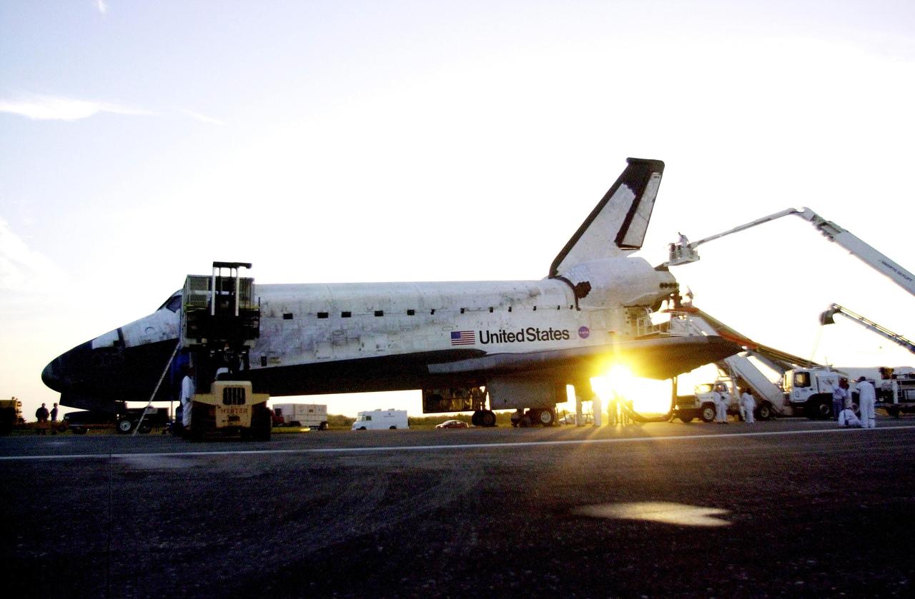 KENNEDY SPACE CENTER, FLA. -- The rising sun blazes from beneath orbiter Columbia as workers prepare the vehicle for ground tow operations. Columbia landed at the KSC Shuttle Landing Facility at 4:33:09 a.m. EST after a successful 11-day mission servicing the Hubble Space Telescope. Main gear touchdown occurred at 4:31:52 a.m. and nose wheel touchdown at 4:32:02. Rollout time was 1 minute, 17 seconds. This was the 58th landing at KSC out of 108 missions in the history of the Shuttle program