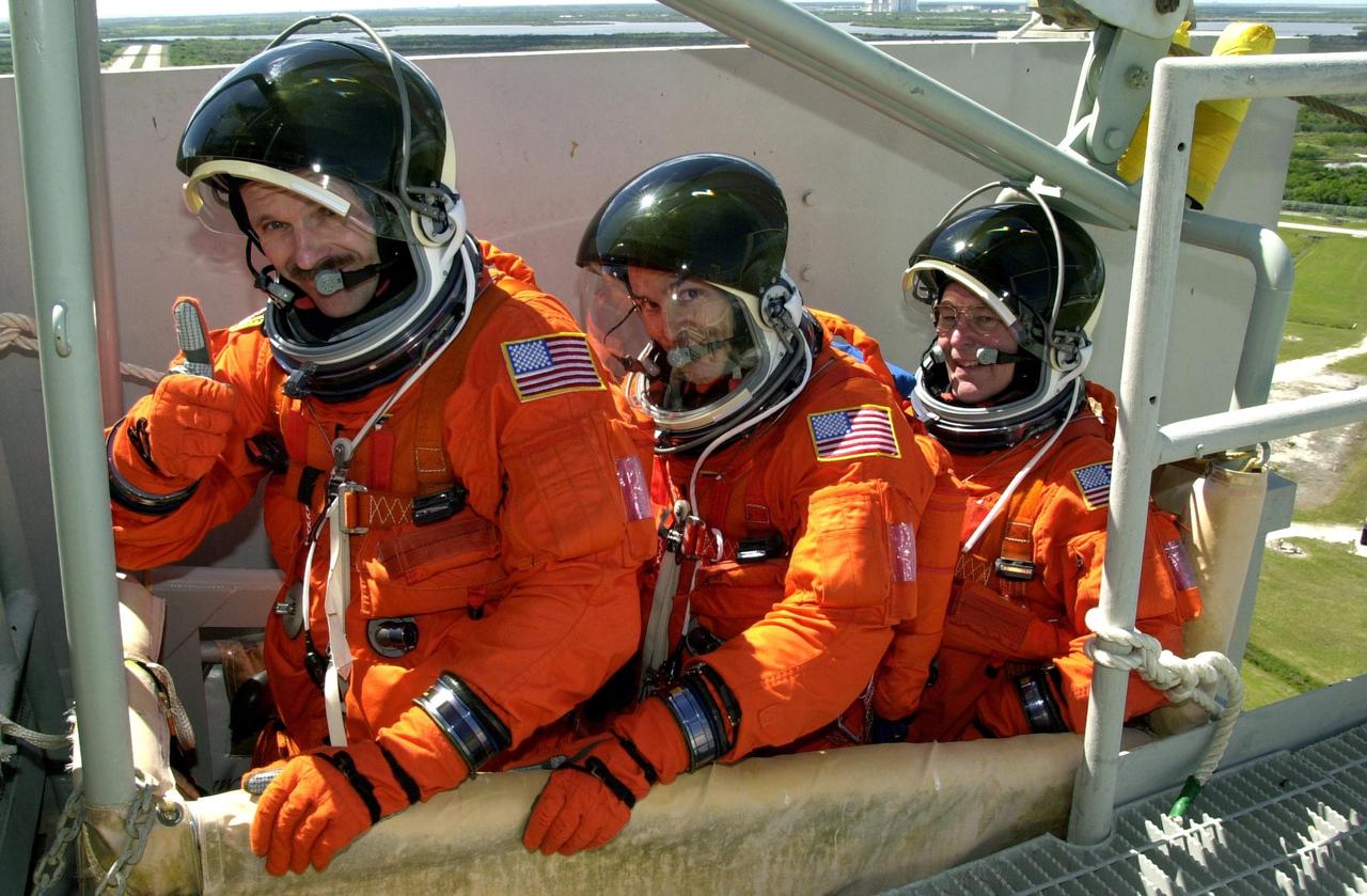 KENNEDY SPACE CENTER, FLA. -- --   STS-110 crew members sit in the slidewire basket, part of emergency egress equipment on the pad.  From left are Mission Specialists Steven L. Smith, Lee M.E. Morin and Jerry L. Ross.  The crew is taking part in Terminal Countdown Demonstration Test activities, which also include a simulated launch countdown, held at KSC prior to each Space Shuttle flight.  Scheduled for launch April 4, the 11-day mission will feature Shuttle Atlantis docking with the International Space Station (ISS) and delivering the S0 truss, the centerpiece-segment of the primary truss structure that will eventually extend over 300 feet.