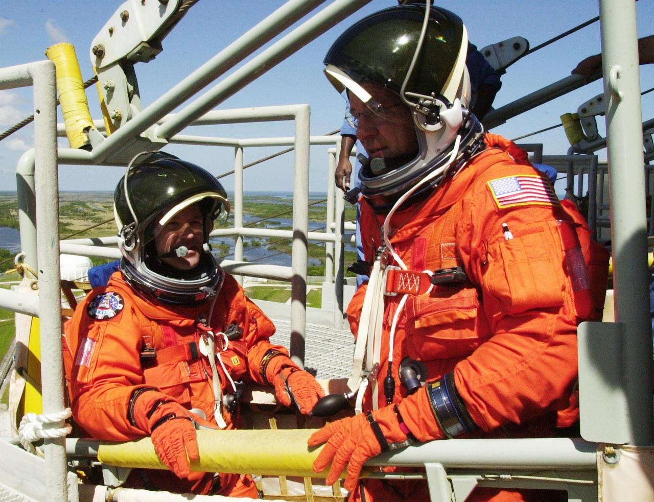 KENNEDY SPACE CENTER, FLA. --  STS-110 Mission Specialists Steven L. Smith (left) and Jerry L. Ross (right) get ready to climb out of the slidewire basket, part of emergency egress equipment on the launch pad.. The crew is taking part in Terminal Countdown Demonstration Test activities, which also include a simulated launch countdown, held at KSC prior to each Space Shuttle flight.  Scheduled for launch April 4, the 11-day mission will feature Shuttle Atlantis docking with the International Space Station (ISS) and delivering the S0 truss, the centerpiece-segment of the primary truss structure that will eventually extend over 300 feet.