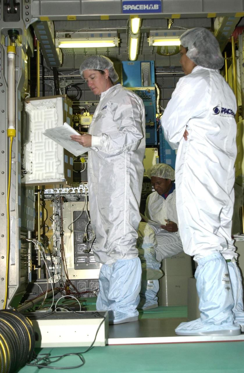 KENNEDY SPACE CENTER, FLA. -- At SPACEHAB, STS-107 crew members check equipment for their mission. From left are Mission Specialist Laurel Clark, Payload Commander Michael Anderson (seated) and Mission Specialist Kalpana Chawla. STS-107 is a research mission. The primary payload is the first flight of the SHI Research Double Module (SHI/RDM). The experiments range from material sciences to life sciences (many rats). Also part of the payload is the Fast Reaction Experiments Enabling Science, Technology, Applications and Research (FREESTAR) that incorporates eight high priority secondary attached shuttle experiments. STS-107 is scheduled to launch July 11, 2002