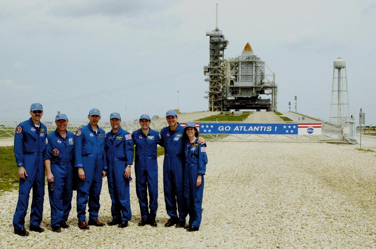 KENNEDY SPACE CENTER, FLA. --  While gathering with friends and family at the pad, the STS-110 crew poses in front of Space Shuttle Atlantis still enclosed by the Rotating Service Structure.  Standing left to right are Mission Specialist Steven Smith, Jerry Ross and Lee Morin; Pilot Stephen Frick; Mission Specialist Rex Walheim; Commander Michael Bloomfield; and Mission Specialist Ellen Ochoa.  The mission continues the expansion of the International Space Station by delivering and installing the S0 Integrated Truss Structure, the initial section of a framework that will eventually hold the power and cooling systems needed for future international research laboratories.  The payload also comprises the Canadian Mobile Transporter (attached to the S0 truss), power distribution system modules, a heat pipe radiator for cooling, computers and a pair of rate gyroscopes. The 11-day mission is the 13th assembly flight to the ISS and includes four spacewalks to attach the S0 truss to the U.S. Lab Destiny.  Launch is scheduled for April 4