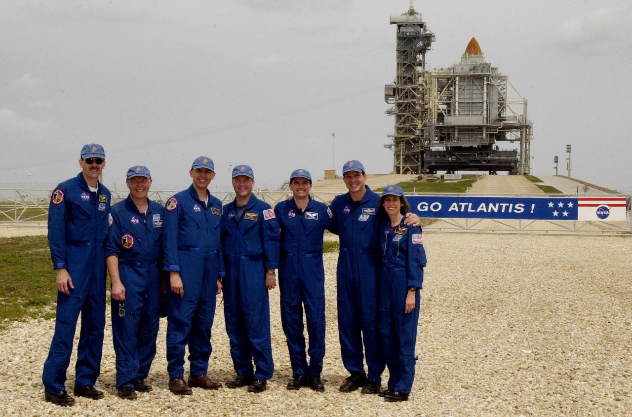 KENNEDY SPACE CENTER, FLA. -- While gathering with friends and family at the pad, the STS-110 crew poses in front of Space Shuttle Atlantis still enclosed by the Rotating Service Structure.  Standing left to right are Mission Specialist Steven Smith, Jerry Ross and Lee Morin; Pilot Stephen Frick; Mission Specialist Rex Walheim; Commander Michael Bloomfield; and Mission Specialist Ellen Ochoa.  The mission continues the expansion of the International Space Station by delivering and installing the S0 Integrated Truss Structure, the initial section of a framework that will eventually hold the power and cooling systems needed for future international research laboratories.  The payload also comprises the Canadian Mobile Transporter (attached to the S0 truss), power distribution system modules, a heat pipe radiator for cooling, computers and a pair of rate gyroscopes. The 11-day mission is the 13th assembly flight to the ISS and includes four spacewalks to attach the S0 truss to the U.S. Lab Destiny.  Launch is scheduled for April 4