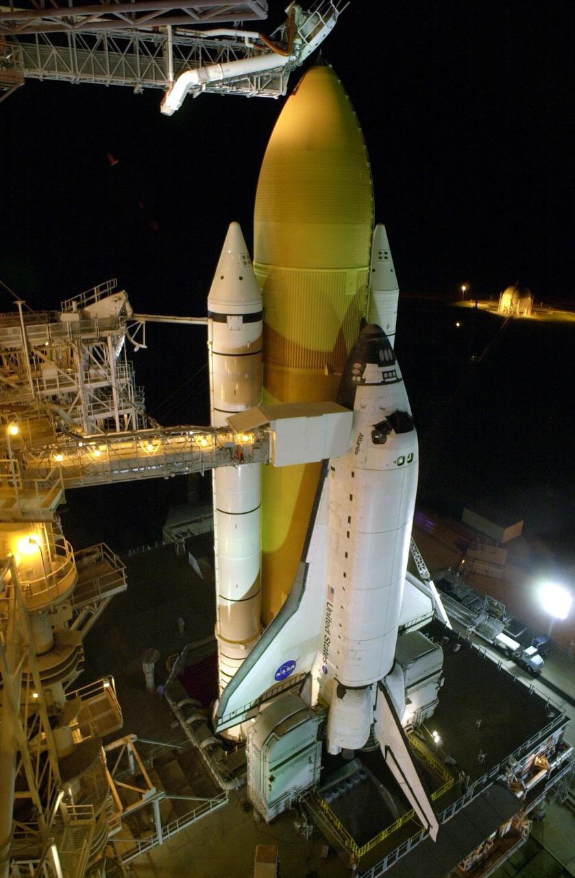 KENNEDY SPACE CENTER, FLA. -- With the Rotating Service Structure rolled back, Space Shuttle Atlantis stands ready for launch on mission STS-110.  The Orbiter Access Arm extends from the Fixed Service Structure (FSS) to the crew compartment hatch, through which the STS-110 crew will enter Atlantis. Above the golden external tank is the vent hood (known as the "beanie cap") at the end of the gaseous oxygen vent arm.  Vapors are created as the liquid oxygen in the external tank boil off.   The hood vents the gaseous oxygen vapors away from the Space Shuttle vehicle.  The RSS provides protected access to the orbiter for changeout and servicing of payloads at the pad.  The structure has access platforms at five levels to provide access to the payload bay.  The FSS provides access to the orbiter and the RSS.  Mission STS-110 is scheduled to launch April 4 on its 11-day mission to the International Space Station