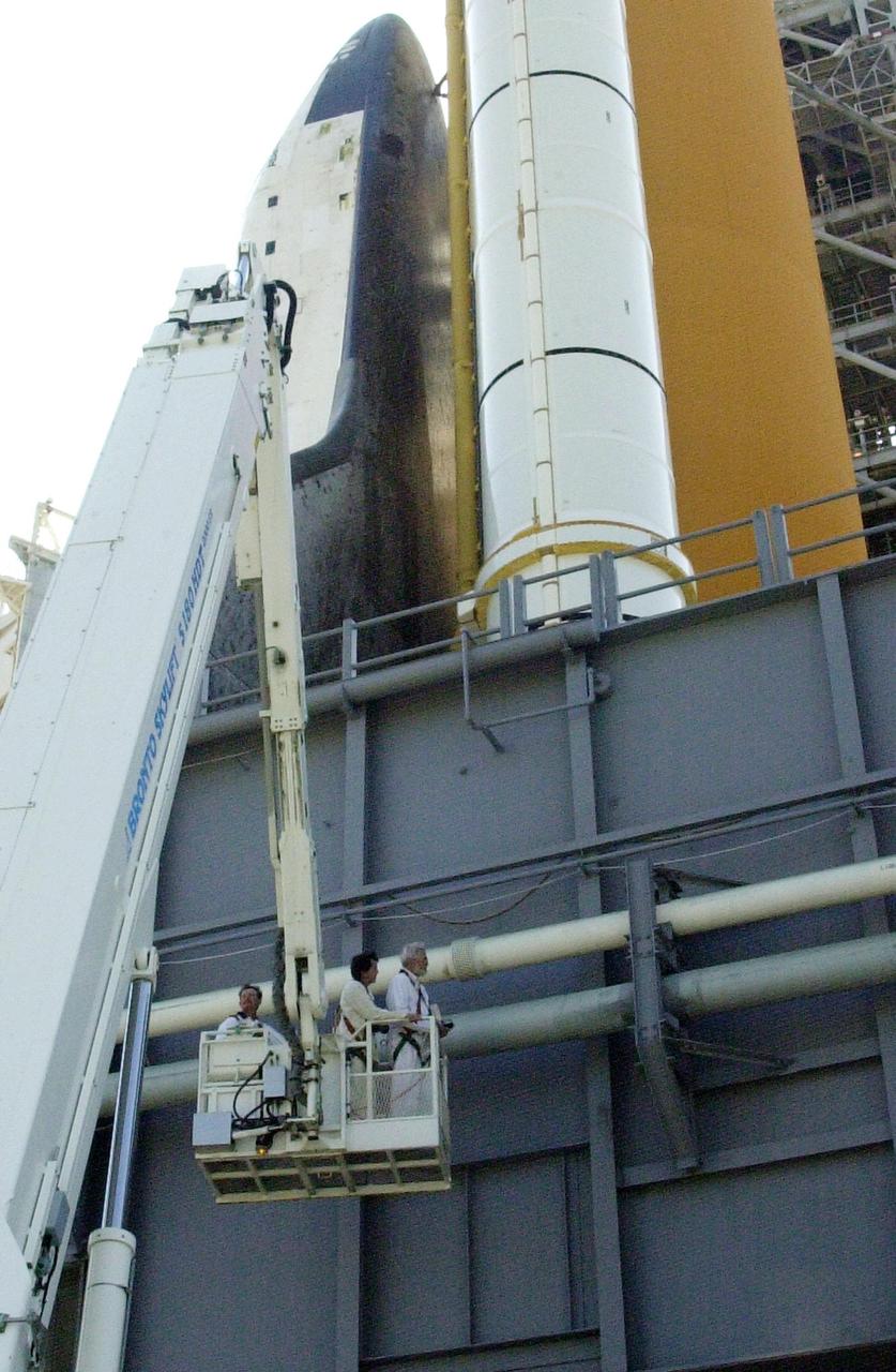 KENNEDY SPACE CENTER, FLA. --  At Launch Pad 39B, workers on a crane inspect pipes on the Mobile Launcher Platform where Space Shuttle Atlantis sits.  Earlier today a leak in a ground support liquid hydrogen vent line on the south side of the Mobile Launcher Platform caused a scrub of the launch of Atlantis on mission STS-110. An engineering team is assessing the situation to determine the best method to repair the hydrogen line.  The turnaround plan includes time to perfor weld repairs and return the vehicle to a timeline to resume the countdown