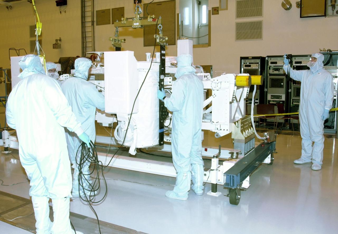 KENNEDY SPACE CENTER, FLA. -- In the Multi-Payload Processing Facility, workers check a GetAway Special canister (GAS can) being moved onto the Hitchhiker Bridge. The bridge is a carrier for the Fast Reaction Experiments Enabling Science, Technology, Applications and Research (FREESTAR) that incorporates eight high priority secondary attached shuttle experiments on mission STS-107. A research mission, the primary payload is the first flight of the SHI Research Double Module (SHI/RDM), also known as SPACEHAB. The experiments range from material sciences to life sciences (many rats). STS-107 is scheduled to launch July 11, 2002