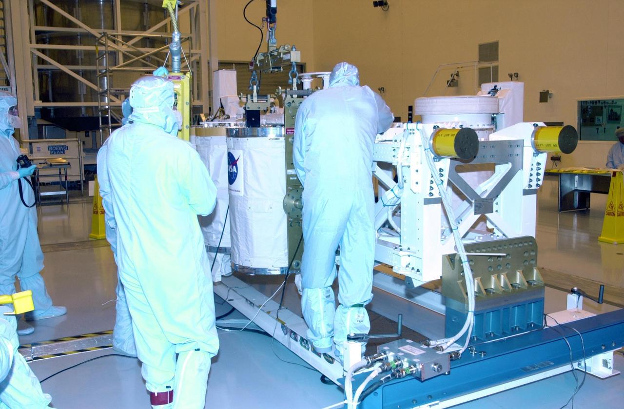KENNEDY SPACE CENTER, FLA. -- In the Multi-Payload Processing Facility, workers check the movement of a GetAway Special canister (GAS can) being lowered onto the Hitchhiker Bridge. The bridge is a carrier for the Fast Reaction Experiments Enabling Science, Technology, Applications and Research (FREESTAR) that incorporates eight high priority secondary attached shuttle experiments on mission STS-107. A research mission, the primary payload is the first flight of the SHI Research Double Module (SHI/RDM), also known as SPACEHAB. The experiments range from material sciences to life sciences (many rats). STS-107 is scheduled to launch July 11, 2002