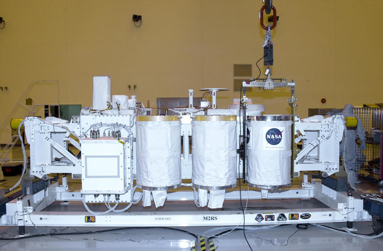 KENNEDY SPACE CENTER, FLA. -- In the Multi-Payload Processing Facility, an overhead crane lowers a GetAway Special canister (GAS can) onto the Hitchhiker Bridge. The bridge is a carrier for the Fast Reaction Experiments Enabling Science, Technology, Applications and Research (FREESTAR) that incorporates eight high priority secondary attached shuttle experiments on mission STS-107. A research mission, the primary payload is the first flight of the SHI Research Double Module (SHI/RDM), also known as SPACEHAB. The experiments range from material sciences to life sciences (many rats). STS-107 is scheduled to launch July 11, 2002
