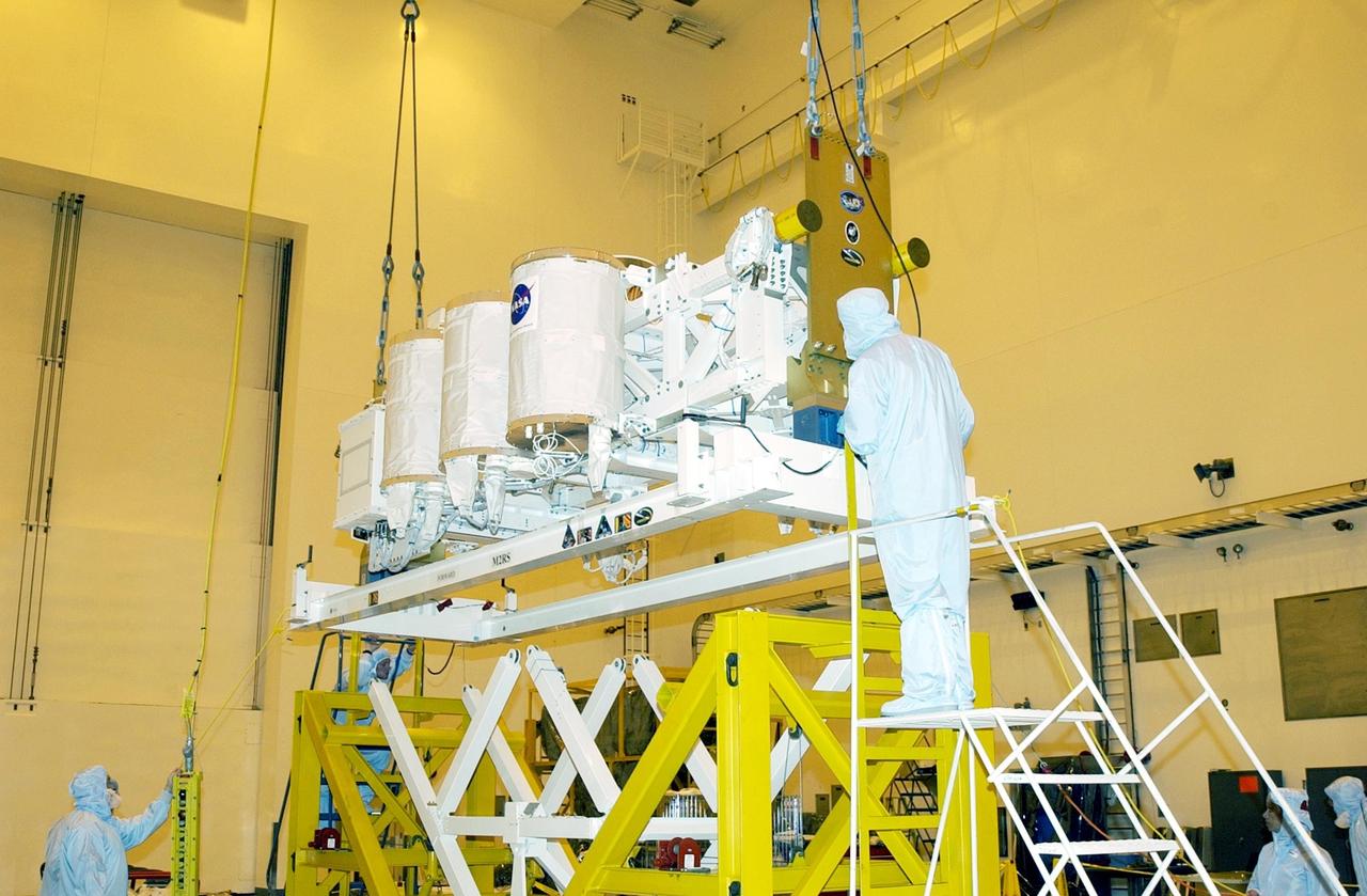 KENNEDY SPACE CENTER, FLA. -- -- In the Multi-Payload Processing Facility (MPPF), the Hitchhiker Bridge is lowered onto a workstand. The bridge is a carrier for the Fast Reaction Experiments Enabling Science, Technology, Applications and Research (FREESTAR) that incorporates eight high priority secondary attached shuttle experiments on mission STS-107. A research mission, the primary payload is the first flight of the SHI Research Double Module (SHI/RDM), also known as SPACEHAB. The experiments range from material sciences to life sciences. STS-107 is scheduled to launch July 11, 2002