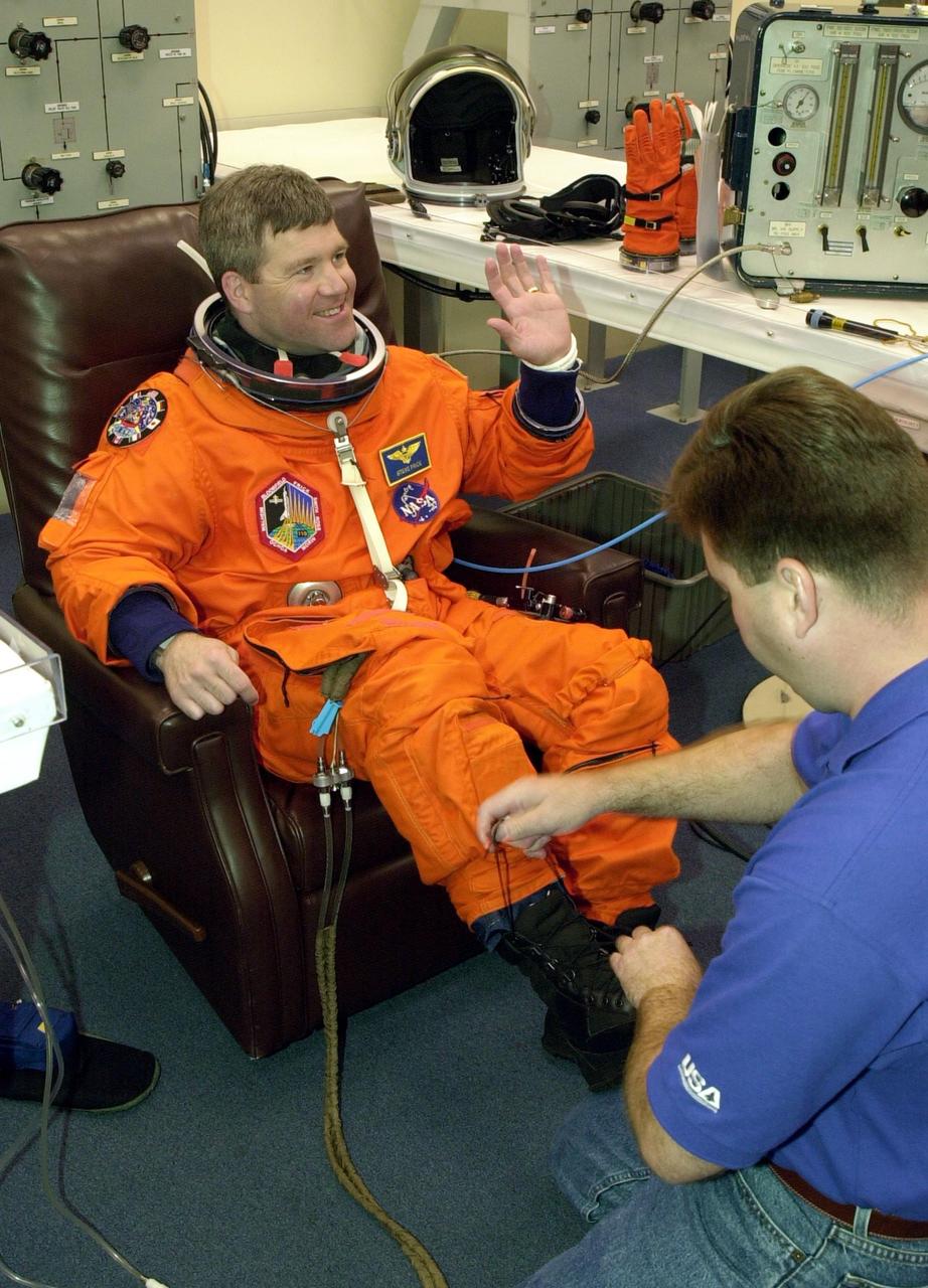 KENNEDY SPACE CENTER, FLA. --  STS-110 Pilot Stephen N. Frick waves while a suit technician makes final adjustments on his launch and entry suit for the launch scheduled for 4:40 p.m. EDT.  Frick is making his first Shuttle flight. STS-110 is the 13th assembly flight to the International Space Station, carrying the S0 Integrated Truss Structure and Mobile Transporter (MT).  On the 11-day mission, the mission features four spacewalks to attach the S0 truss, which will become the backbone of the Space Station, to the U.S. Lab, "Destiny."   The  MT, a space "railcar," is attached to the truss segment and will make its debut run during the flight