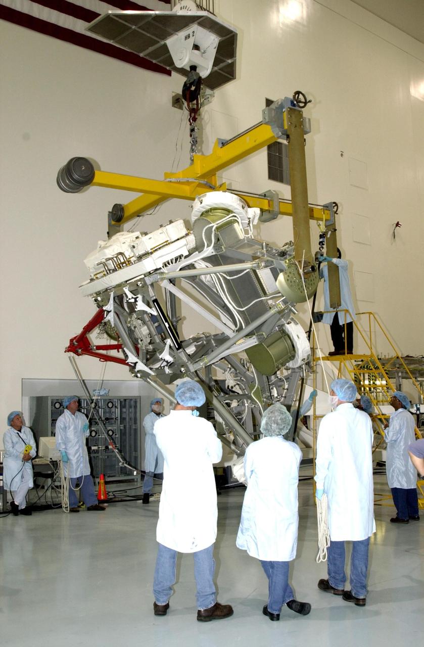 KENNEDY SPACE CENTER, FLA. -- In the Space Station Processing Facility, workers keep watch while overhead cranes lift the Mobile Base System before moving it to the weight and center of gravity stand. Part of the payload on mission STS-111 to the International Space Station, the MBS will be installed on the Mobile Transporter to complete the Canadian Mobile Servicing System, or MSS. The mechanical arm will then have the capability to "inchworm" from the U.S. Lab Destiny to the MSS and travel along the truss to work sites. STS-111 is the second utilization flight (UF-2) to the Space Station and will also carry the Expedition 5 crew to replace Expedition 4. Launch is scheduled for May 31, 2002