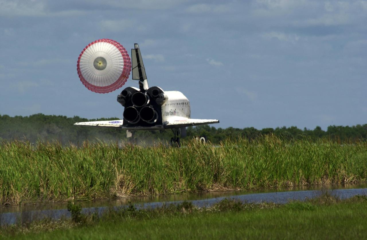 KENNEDY SPACE CENTER, FLA. - Atlantis, with its drag chute deployed, finds the runway beyond the vegetation at KSC's Shuttle Landing Facility.  The landing completes the 10-day, 19-hour, 4.5-million mile mission STS-110 to the International Space Station. The orbiter carries the returning crew Commander Michael Bloomfield, Pilot Stephen Frick and Mission Specialists Jerry Ross, Steven Smith, Ellen Ochoa, Lee Morin and Rex Walheim.  Main gear touchdown was 12:26:57 p.m. EDT, nose gear touchdown was 12:27:09 p.m. and wheel stop was 12:28:07 p.m.  The crew delivered and installed the S0 truss, which will support cooling and power systems essential for the addition of future international laboratories, on the Station