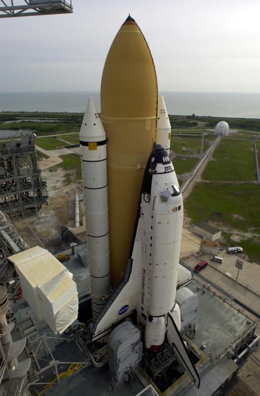 KENNEDY SPACE CENTER, FLA. - Space Shuttle Endeavour rests on Launch Pad 39A after rollout from the Vehicle Assembly Building.  The Shuttle comprises the orbiter, in front, and the taller orange external tank behind it flanked by twin solid rocket boosters.  The Shuttle sits on the Mobile Launcher Platform that straddles the flame trench below.  On either side of Endeavour's tail and main engines are the tail service masts that support the fluid,, gas and electrical requirements of the orbiter's liquid oxyen and liquid hydrogen aft T-0 umbilicals.  In the foreground, left, is the White Room, located at the end of the orbiter access arm.  This environmentally controlled area provides access to the cockpit of the orbiter. Mission STS-111 is designated UF-2, the 14th assembly flight to the International Space Station.  Endeavour's payload includes the Multi-Purpose Logistics Module Leonardo and Mobile Base System.  The mission also will swap resident crews on the Station, carrying the Expedition 5 crew and returning to Earth Expedition 4.  Liftoff of Endeavour is scheduled between 4 and 8 p.m. May 30, 2002