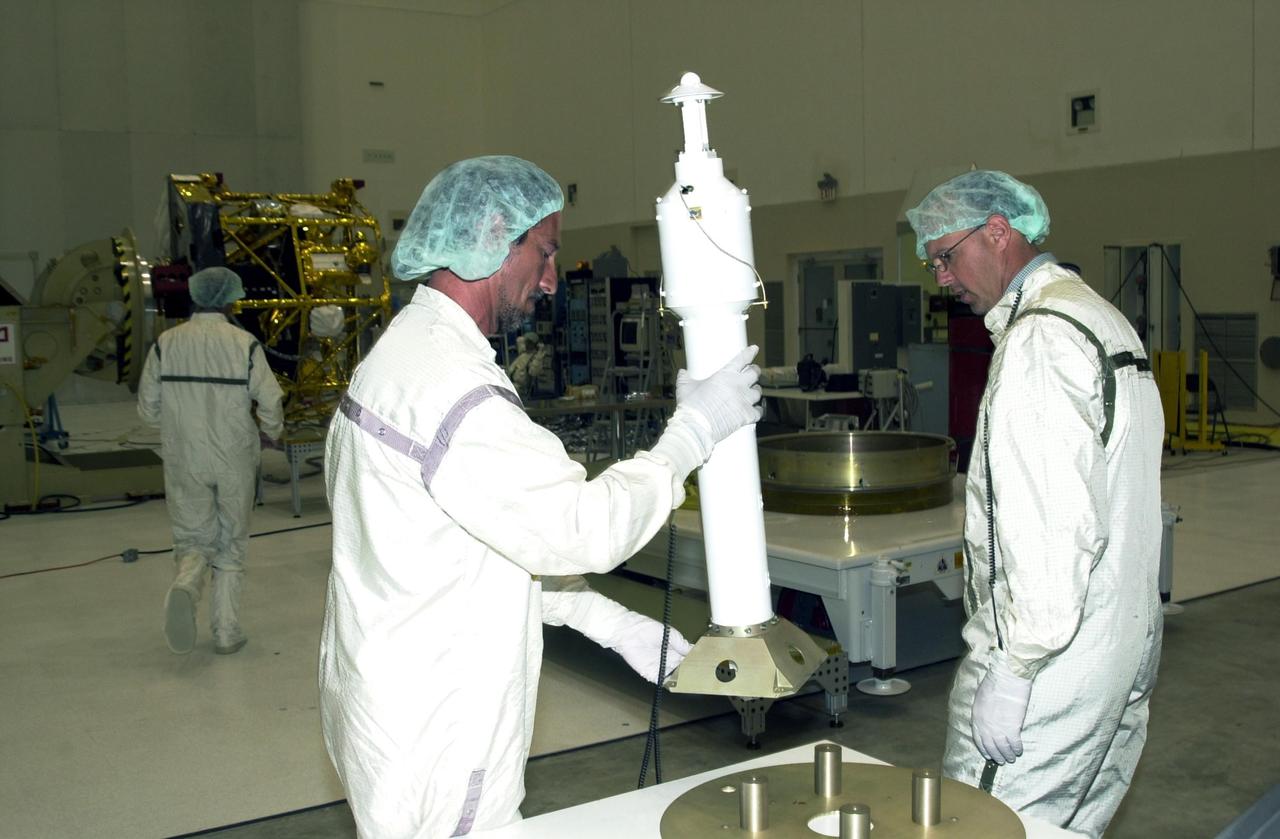 KENNEDY SPACE CENTER, FLA. -- Workers in the Spacecraft Assembly and Encapsulation Facility 2 (SAEF-2) move the antenna that is to be installed on the solar panel for the Comet Nucleus Tour (CONTOUR) spacecraft (seen in the background). CONTOUR will provide the first detailed look into the heart of a comet -- the nucleus. The spacecraft will fly as close as 60 miles (100 kilometers) to at least two comets, Encke and Schwassmann-Wachmann 3. It will take the sharpest pictures yet of the nucleus while analyzing the gas and dust that surround these rocky, icy building blocks of the solar system. The Applied Physics Laboratory of Johns Hopkins University, Baltimore, Md., built CONTOUR and will also be in control of the spacecraft after launch, which is scheduled for July 1, 2002, from LC 17A at Cape Canaveral Air Force Station