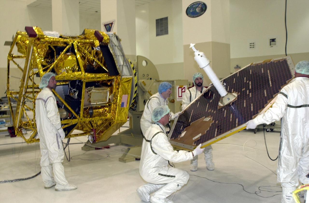 KENNEDY SPACE CENTER, FLA. -- In the Spacecraft Assembly and Encapsulation Facility 2 (SAEF-2), workers lift the solar panel and attached antenna to move it to the Comet Nucleus Tour (CONTOUR) spacecraft at left. Scheduled for launch July 1, 2002, from LC 17A at Cape Canaveral Air Force Station, CONTOUR will provide the first detailed look into the heart of a comet -- the nucleus. The spacecraft will fly as close as 60 miles (100 kilometers) to at least two comets, Encke and Schwassmann-Wachmann 3. It will take the sharpest pictures yet of the nucleus while analyzing the gas and dust that surround these rocky, icy building blocks of the solar system. The Applied Physics Laboratory of Johns Hopkins University, Baltimore, Md., built CONTOUR and will also be in control of the spacecraft after launch