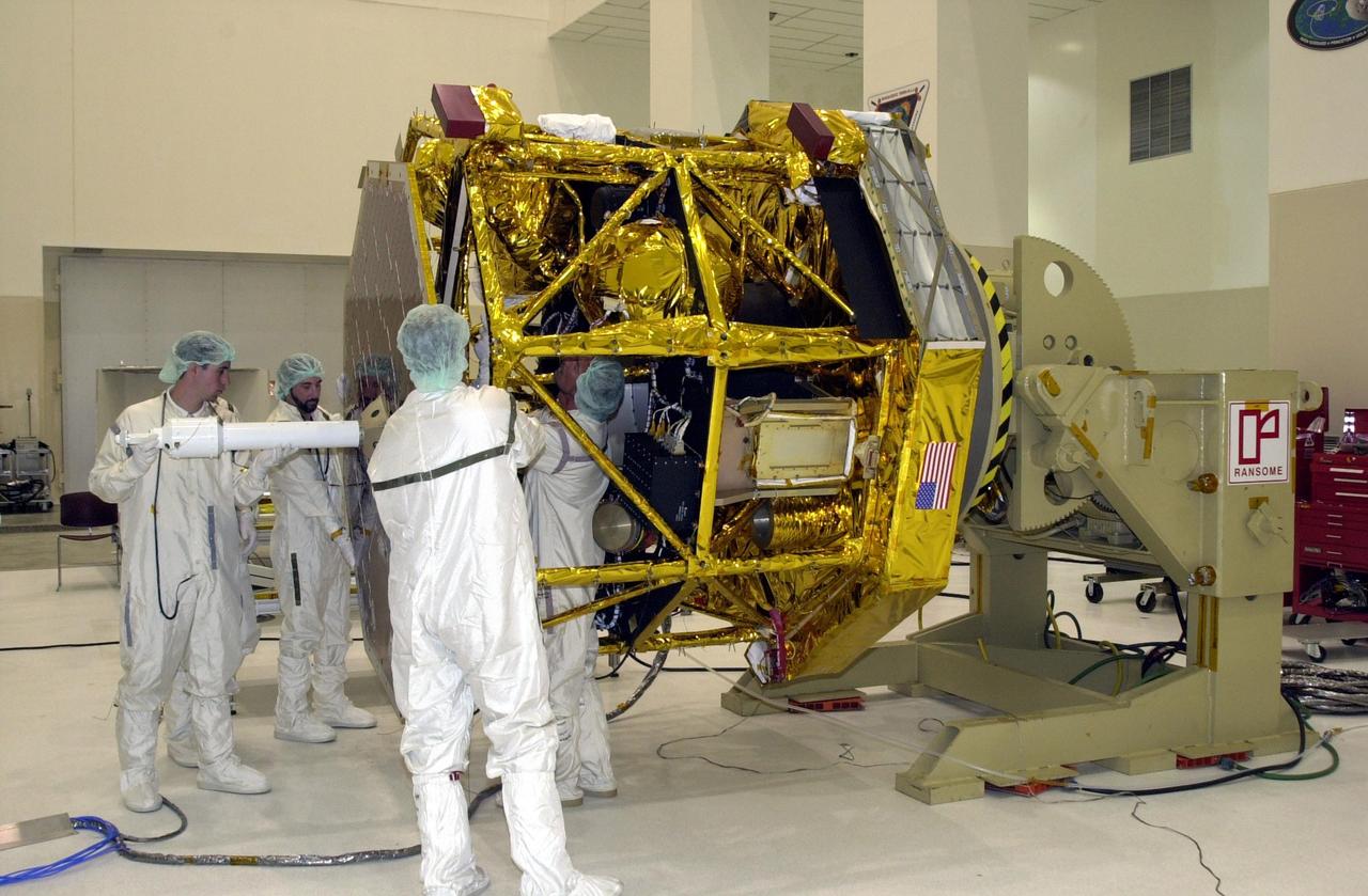 KENNEDY SPACE CENTER, FLA. -- In the Spacecraft Assembly and Encapsulation Facility 2 (SAEF-2), workers at left hold the antenna and solar panel steady while make adjustments before attaching it to the Comet Nucleus Tour (CONTOUR) spacecraft. Scheduled for launch July 1, 2002, from LC 17A at Cape Canaveral Air Force Station, CONTOUR will provide the first detailed look into the heart of a comet -- the nucleus. The spacecraft will fly as close as 60 miles (100 kilometers) to at least two comets, Encke and Schwassmann-Wachmann 3. It will take the sharpest pictures yet of the nucleus while analyzing the gas and dust that surround these rocky, icy building blocks of the solar system. The Applied Physics Laboratory of Johns Hopkins University, Baltimore, Md., built CONTOUR and will also be in control of the spacecraft after launch