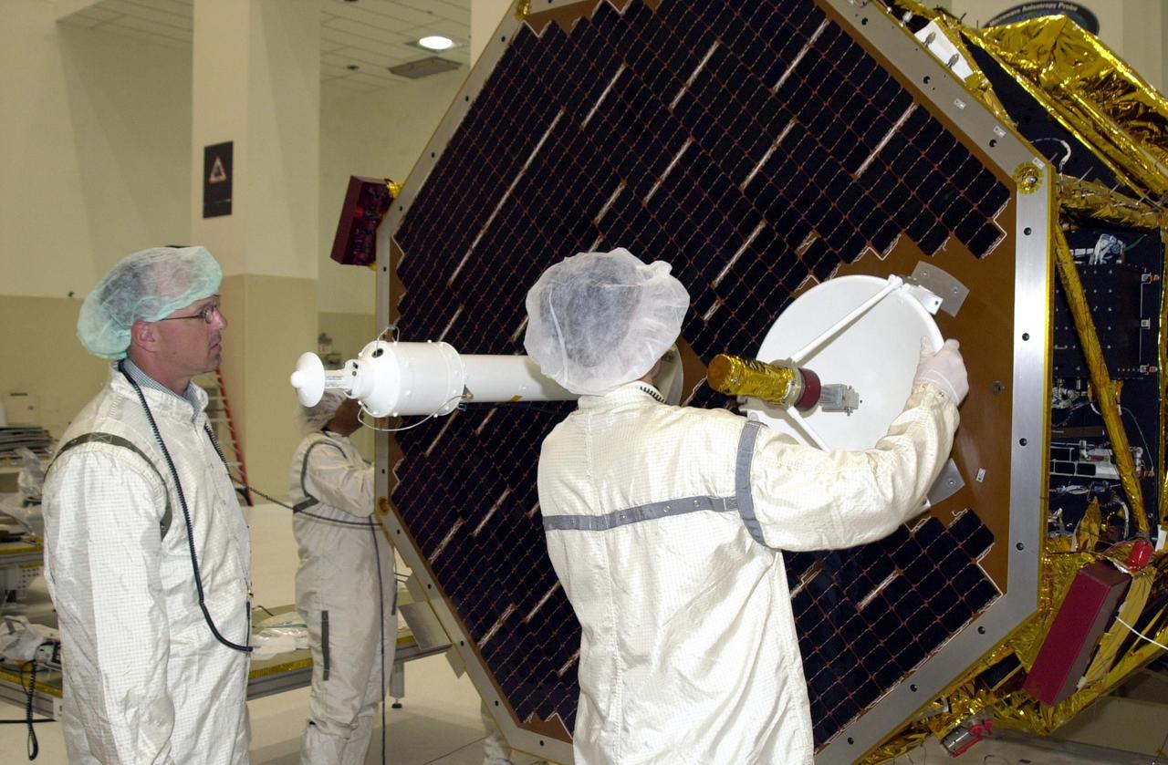 KENNEDY SPACE CENTER, FLA. -- While a co-worker (left) looks on, a worker (right) places the high gain antenna onto the solar panel of the Comet Nucleus Tour (CONTOUR) spacecraft. Scheduled for launch July 1, 2002, from LC 17A at Cape Canaveral Air Force Station, CONTOUR will provide the first detailed look into the heart of a comet -- the nucleus. The spacecraft will fly as close as 60 miles (100 kilometers) to at least two comets, Encke and Schwassmann-Wachmann 3. It will take the sharpest pictures yet of the nucleus while analyzing the gas and dust that surround these rocky, icy building blocks of the solar system. The Applied Physics Laboratory of Johns Hopkins University, Baltimore, Md., built CONTOUR and will also be in control of the spacecraft after launch