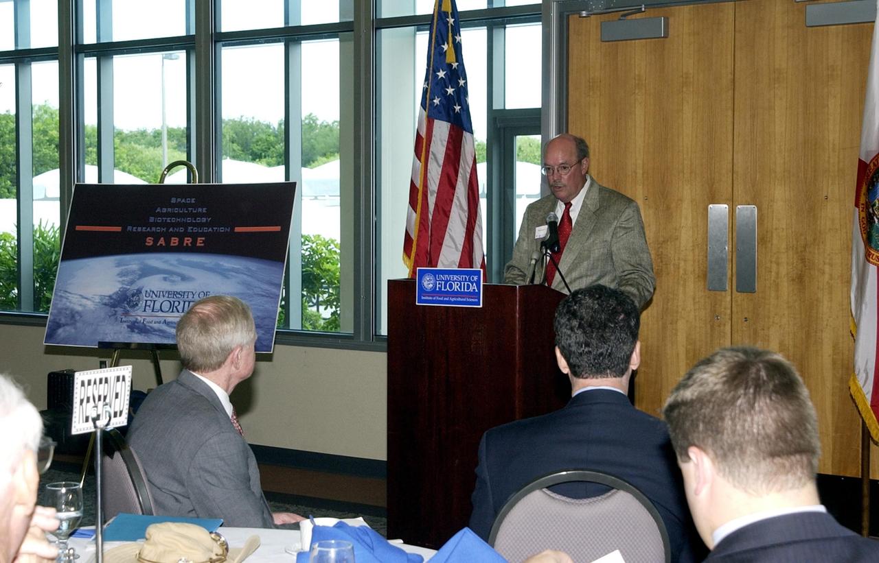KENNEDY SPACE CENTER, FLA. -- Mike Martin, University of Florida vice president for agriculture and natural resources, speaks during the opening ceremony to launch a new program called SABRE, Space Agricultural Biotechnology Research and Education, that involves UF and NASA.  Officials from UF and NASA attended the event.  In the foreground are Center Director Roy D. Bridges Jr. (left) and U.S. Rep. Dave Weldon (right).  SABRE will focus on the discovery, development and application of the biological aspects of advanced life support strategies. The program will include faculty from UF's Institute of Food and Agricultural Sciences, who will be located at both KSC - in the state-owned Space Experiment Research and Processing Laboratory (SERPL) being built there - and UF in Gainesville.  SABRE will be directed by Robert Ferl, professor in the horticultural sciences department and assistant director of UF's Biotechnology Program.  He will be responsible for coordinating the research and education efforts of UF and NASA
