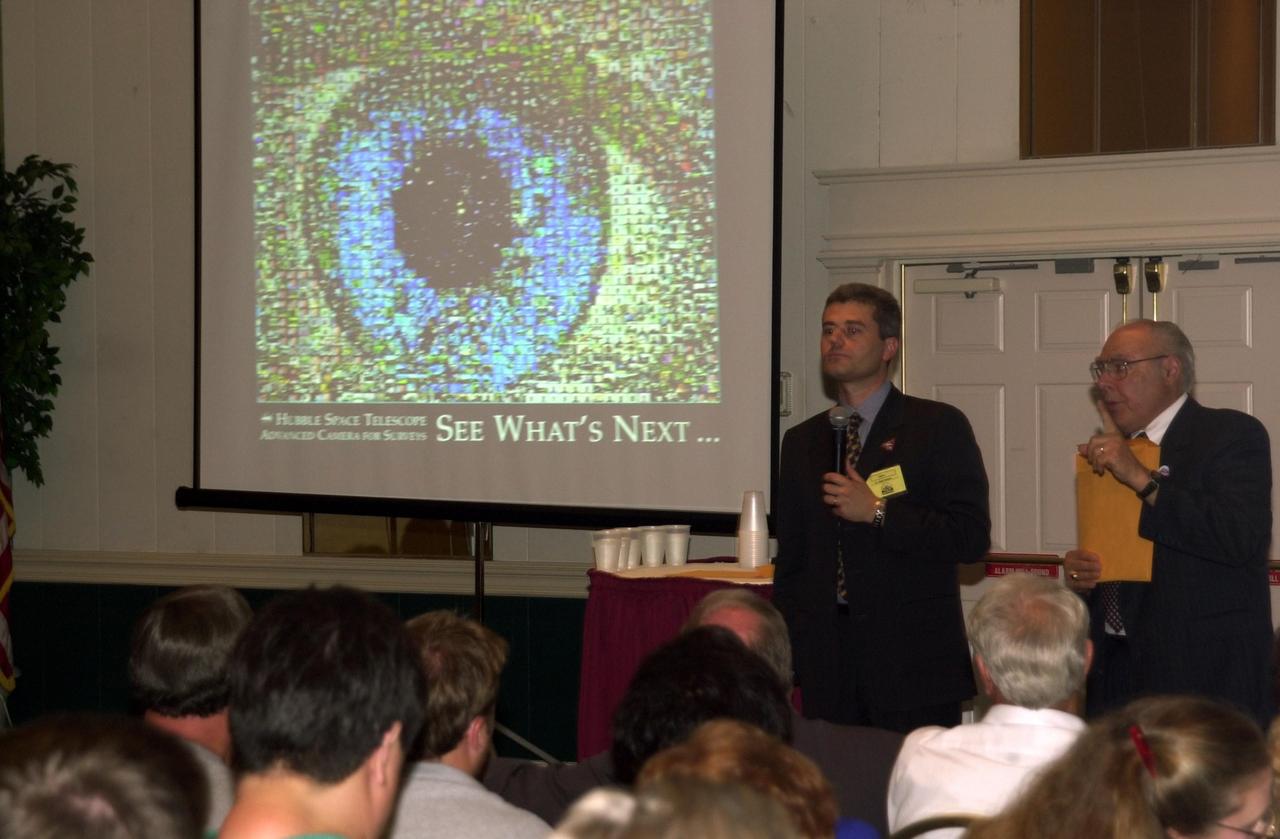 KENNEDY SPACE CENTER, FLA. -- At the 2002 Space Congress, Cape Canaveral, Fla., a presentation on "Hubble Discoveries" by Dr. Mark Clampin (with microphone), Advanced Camera for Surveys team, included an image of an eye (seen on the screen) comprising hundreds of photos of all the people who worked on Hubble. On the right is Frank Ceppolina, project manager, Hubble Space Telescope Development Project.   The Space Congress is held annually to highlight military and space initiatives, new technologies, and Florida's role in programs and research.  This year's theme is Beginning a New Era - Initiatives in Space. NASA presented several paper sessions, including Advancements in Technology.  Space Congress is sponsored by the Canaveral Council of Technical Societies