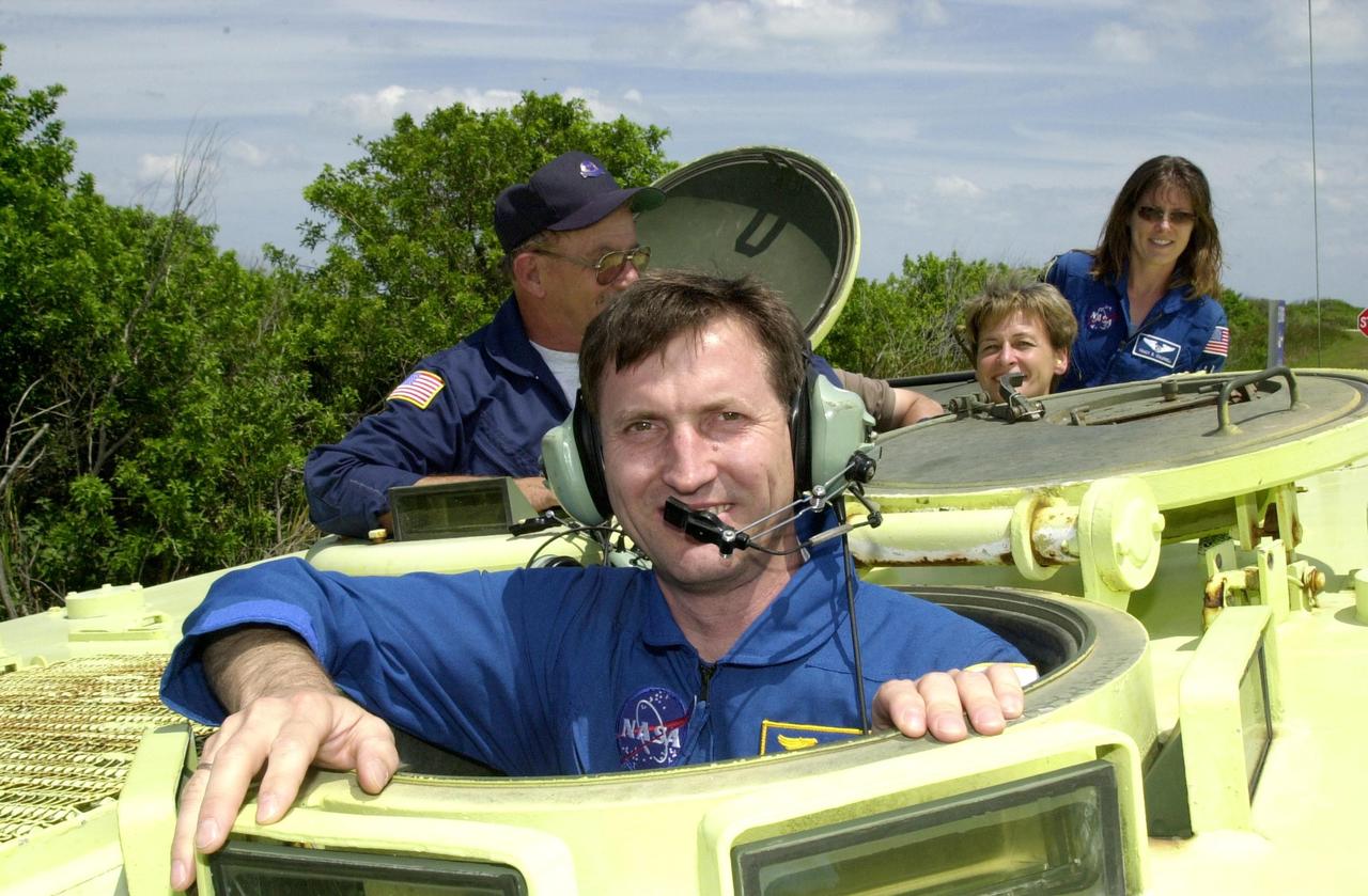 KENNEDY SPACE CENTER, FLA. -- During Terminal Countdown Demonstration Test activities at KSC, Expedition 5 crew member Sergei Treschev pauses before climbing inside the M-113 armored personnel carrier, used for emergency egress training at the pad. At left (behind Treschev) is George Hoggard, with the KSC/CCAS Fire Department, who supervises the driving. At right are Expedition 5 member Peggy Whitson and astronaut Tracy Caldwell (far right), a mission specialist candidate currently assigned to the Astronaut Office Space Station Operations Branch. The TCDT also includes a simulated launch countdown Known as Utilization Flight -2, the mission includes attaching a Canadian-built mobile base system to the International Space Station that will enable the Canadarm2 robotic arm to move along a railway on the Station's truss to build and maintain the outpost. The crew will also replace a faulty wrist/roll joint on the Canadarm2 as well as unload almost three tons of experiments and supplies from the Italian-built Multi-Purpose Logistics Module Leonardo. . Expedition 5 will travel to the International Space Station on mission STS-111 as the replacement crew for Expedition 4, who will return to Earth aboard Endeavour. Launch of Space Shuttle Endeavour on mission STS-111 is scheduled for May 30, 2002