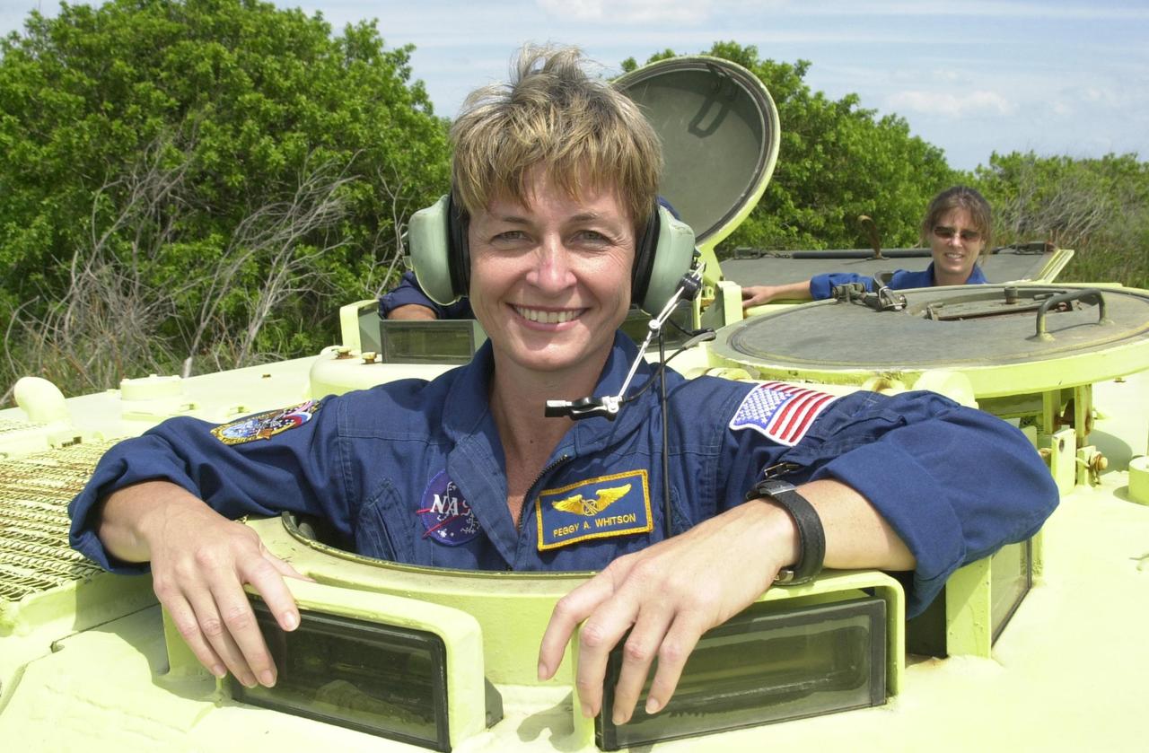 KENNEDY SPACE CENTER, FLA. -- During Terminal Countdown Demonstration Test activities at KSC, Expedition 5 member Peggy Whitson poses for the camera before climbing inside the M-113 armored personnel carrier, used for emergency egress training at the pad. Behind her (right) is astronaut Tracy Caldwell, a mission specialist candidate currently assigned to the Astronaut Office Space Station Operations Branch. Expedition 5 will travel to the International Space Station on mission STS-111 as the replacement crew for Expedition 4, who will return to Earth aboard Endeavour. The TCDT also includes a simulated launch countdown Known as Utilization Flight -2, the mission includes attaching a Canadian-built mobile base system to the International Space Station that will enable the Canadarm2 robotic arm to move along a railway on the Station's truss to build and maintain the outpost. The crew will also replace a faulty wrist/roll joint on the Canadarm2 as well as unload almost three tons of experiments and supplies from the Italian-built Multi-Purpose Logistics Module Leonardo. Launch of Space Shuttle Endeavour on mission STS-111 is scheduled for May 30, 2002
