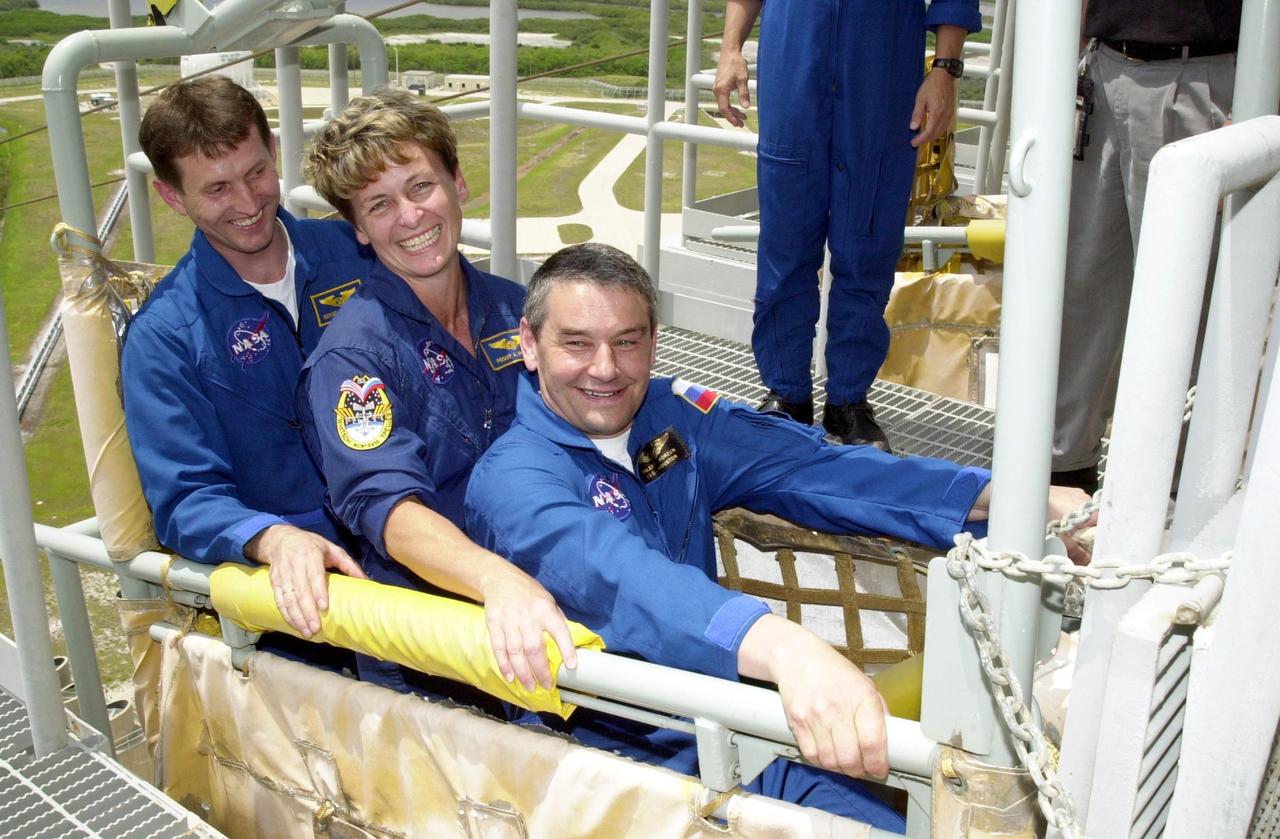 KENNEDY SPACE CENTER, FLA. --  Expedition 5 crew members test the slidewire basket on Launch Pad 39A as part of emergency egress training at the pad.  From left are Sergei Treschev, Peggy Whitson and Commander Valeri Korzun.  The training is part of Terminal Countdown Demonstration Test activities for Expedition 5 and the STS-111 crew.  The TCDT also includes a simulated launch countdown.  Mission STS-111 is known as Utilization Flight 2, carrying supplies and equipment in the Multi-Purpose Logistics Module Leonardo to the International Space Station.  The payload also includes the Mobile Base System, which will be installed on the Mobile Transporter to complete the Canadian Mobile Servicing System, or MSS, and a replacement wrist/roll joint for Canadarm 2. The mechanical arm will then have the capability to "inchworm" from the U.S. Lab Destiny to the MSS and travel along the truss to work sites.   Expedition 5 will travel to the Station on Endeavour as the replacement crew for Expedition 4, who will return to Earth aboard the orbiter.  Launch is scheduled for May 30, 2002