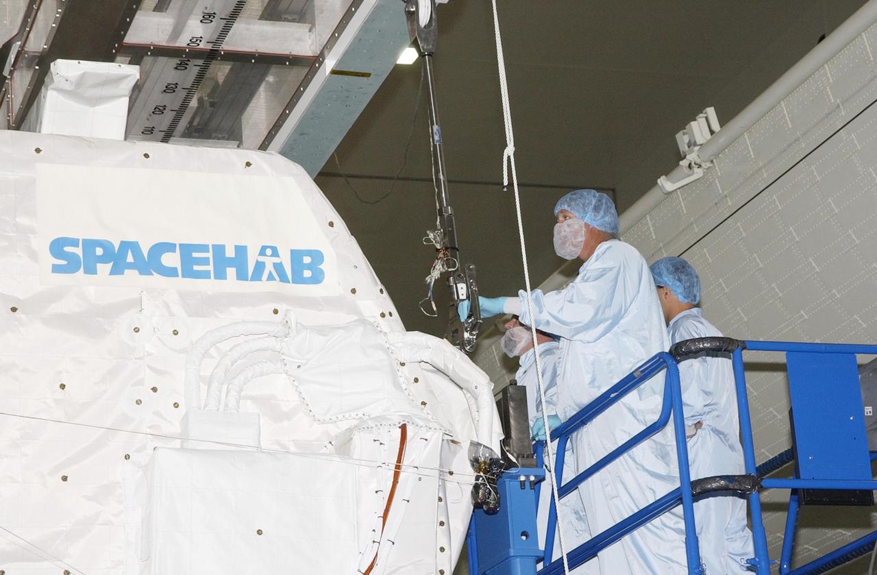 KENNEDY SPACE CENTER, FLA. - Workers in the Space Station Processing Facility attach the overhead crane to the SHI Research Double Module (SHI/RDM) to lift it off the workstand.  The module is being transferred to the payload canister for transport to the Orbiter Processing Facility where it will be installed in Columbia's payload bay for mission STS-107. SHI/RDM is the primary payload of the research mission, with experiments ranging from material sciences to life sciences (many rats).  Also part of the payload is the Fast Reaction Experiments Enabling Science, Technology, Applications and Research (FREESTAR) that incorporates eight high priority secondary attached shuttle experiments.  STS-107 is scheduled to launch July 19, 2002
