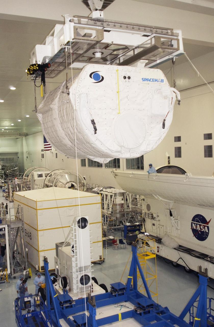 KENNEDY SPACE CENTER, FLA. - Suspended from the overhead crane, the SHI Research Double Module (SHI/RDM) travels across the Space Station Processing Facility to the payload canister waiting at right.  The module will be placed in the canister for transport to the Orbiter Processing Facility where it will be installed in Columbia's payload bay for mission STS-107. SHI/RDM is the primary payload of the research mission, with experiments ranging from material sciences to life sciences (many rats).  Also part of the payload is the Fast Reaction Experiments Enabling Science, Technology, Applications and Research (FREESTAR) that incorporates eight high priority secondary attached shuttle experiments.  STS-107 is scheduled to launch July 19, 2002