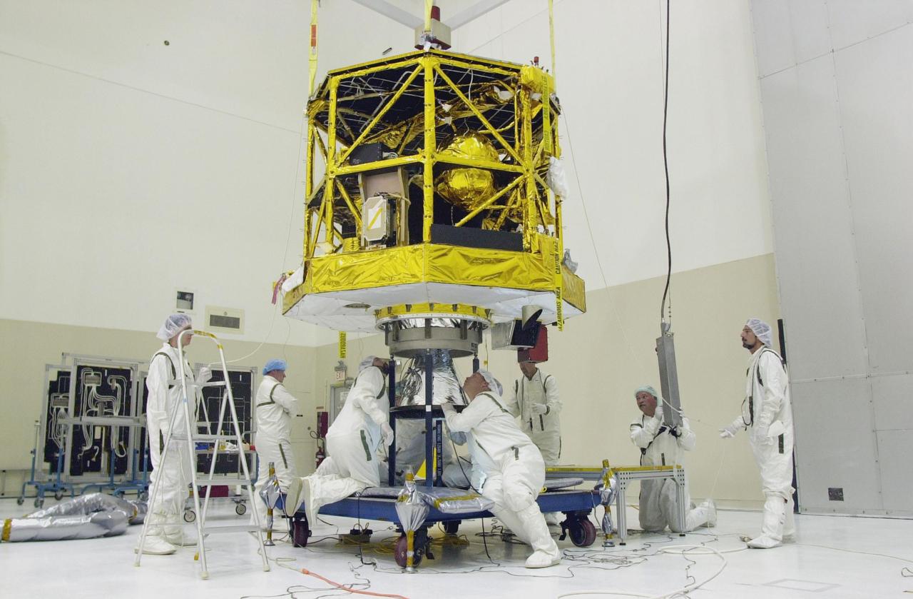 KENNEDY SPACE CENTER, FLA. - Workers in the Spacecraft Assembly and Encapsulation Facility 2 check the position of the CONTOUR spacecraft as it is lowered over the apogee kick motor to which it will be attached. CONTOUR will provide the first detailed look into the heart of a comet -- the nucleus. The spacecraft will fly close to at least two comets, Encke and Schwassmann-Wachmann 3, taking pictures of the nucleus while analyzing the gas and dust that surround these rocky, icy building blocks of the solar system. The Applied Physics Laboratory of Johns Hopkins University, Baltimore, Md., built CONTOUR and will also be in control of the spacecraft after launch, scheduled for July 1, 2002, from LC 17A at Cape Canaveral Air Force Station