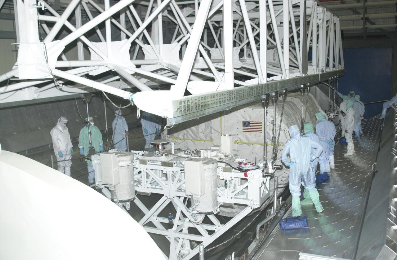 KENNEDY SPACE CENTER, FLA. - In the Orbiter Processing Facility, an overhead crane is attached to the SHI Research Double Module (SHI/RDM) (right) and Hitchhiker Carrier (left) to lift them out of the payload canister. They will be installed in Columbia's payload bay. SHI/RDM is the primary payload of the STS-107 research mission, with experiments ranging from material sciences to life sciences (many rats). Also, the Fast Reaction Experiments Enabling Science, Technology, Applications and Research (FREESTAR) that is on the Hitchhiker Carrier incorporates eight high priority secondary attached shuttle experiments. STS-107 is scheduled to launch July 19, 2002