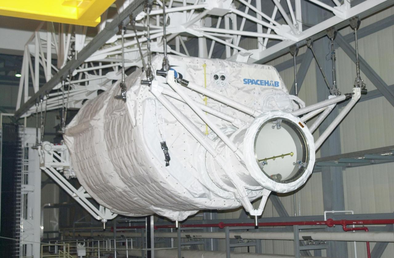 KENNEDY SPACE CENTER, FLA. -- In the Orbiter Processing Facility, the Hitchhiker Carrier (front) and the SHI Research Double Module (SHI/RDM) behind it are suspended over Columbia's payload bay. The two payloads will be installed in the payload bay for mission STS-107, a research mission. SHI/RDM is the primary payload, with experiments ranging from material sciences to life sciences (many rats). Also, the Fast Reaction Experiments Enabling Science, Technology, Applications and Research (FREESTAR) that is on the Hitchhiker Carrier incorporates eight high priority secondary attached shuttle experiments. STS-107 is scheduled to launch July 19, 2002